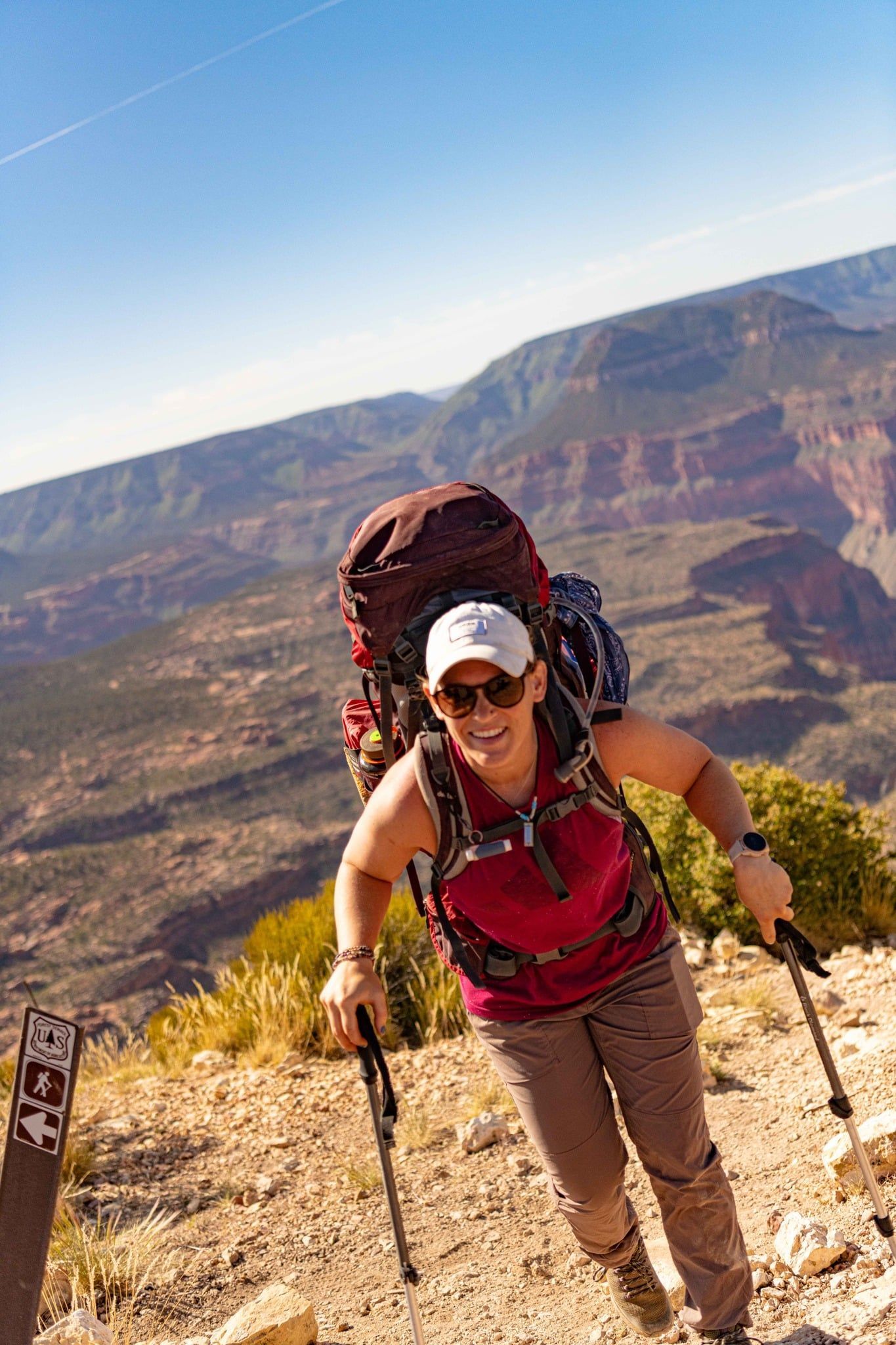 A woman with a backpack is hiking up a mountain.