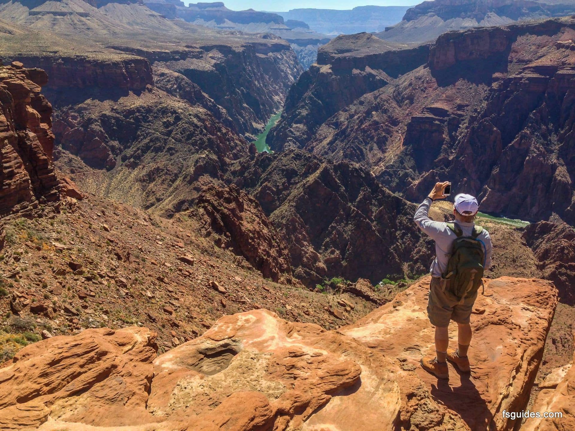 A man taking a picture of a canyon with his phone