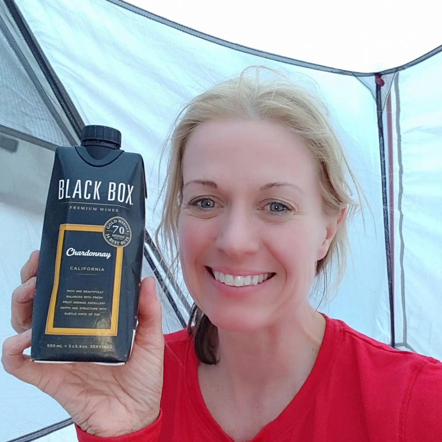 A woman is holding a carton of black box chardonnay