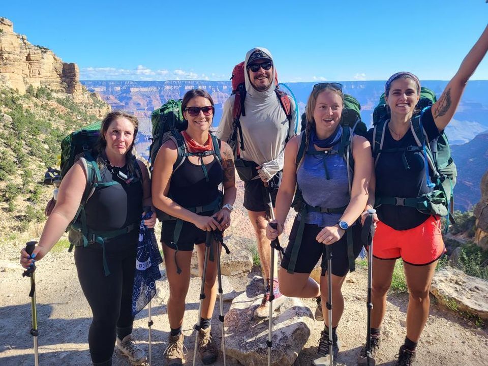 A group of people standing next to each other on top of a mountain.