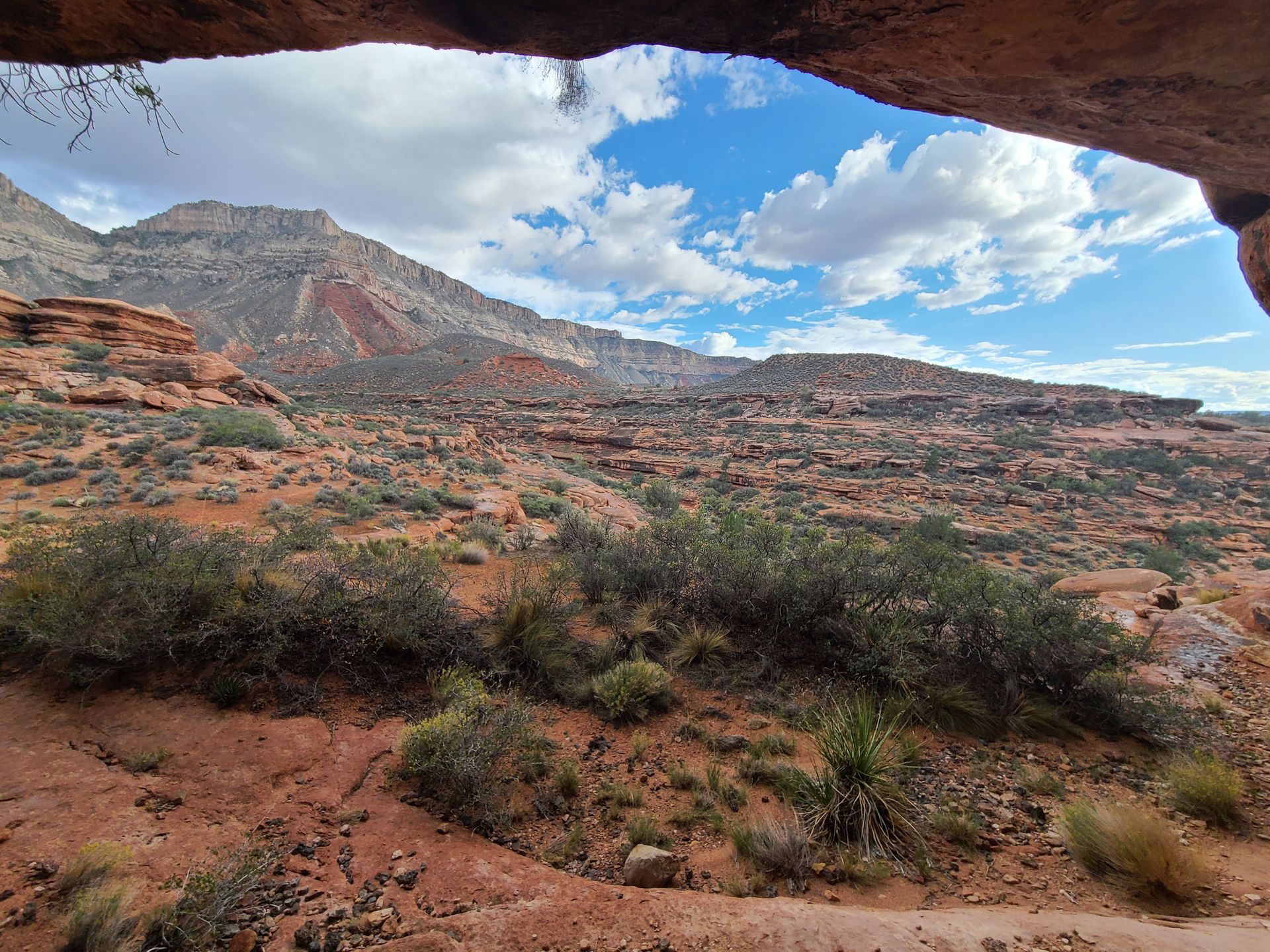 A view of a desert landscape from a cave with mountains in the background.