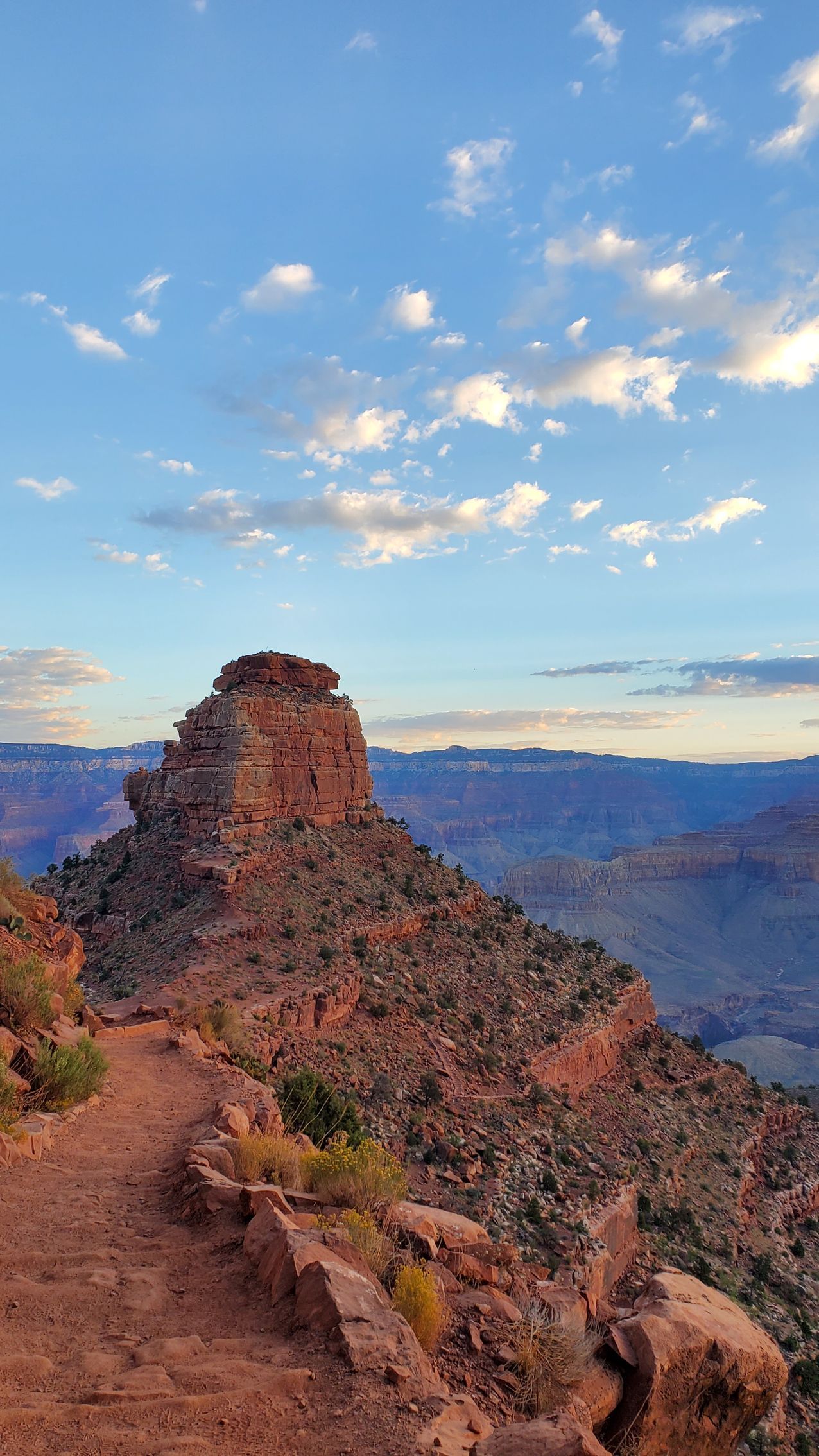 A mountain with a trail going up to it and a view of the grand canyon.