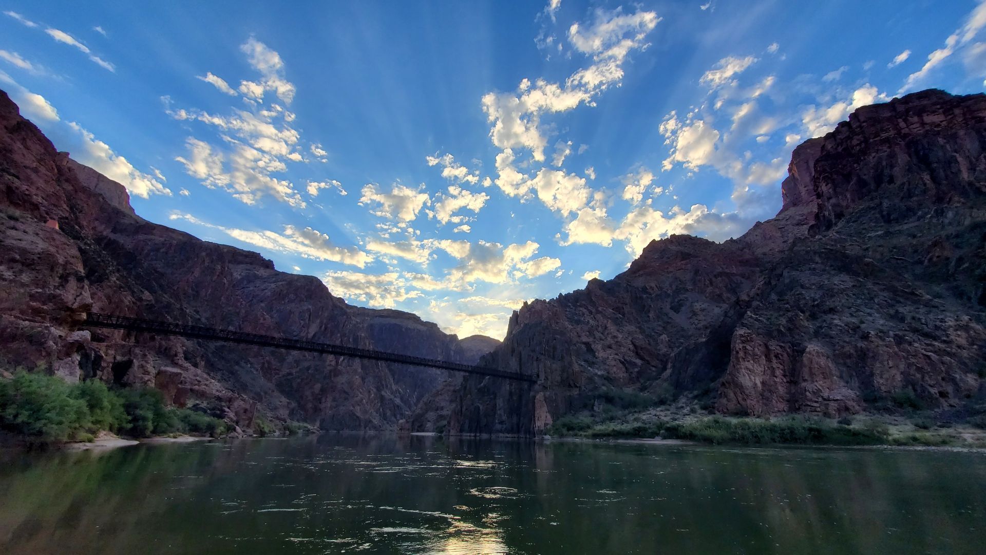 There is a bridge over a river in the middle of a canyon.
