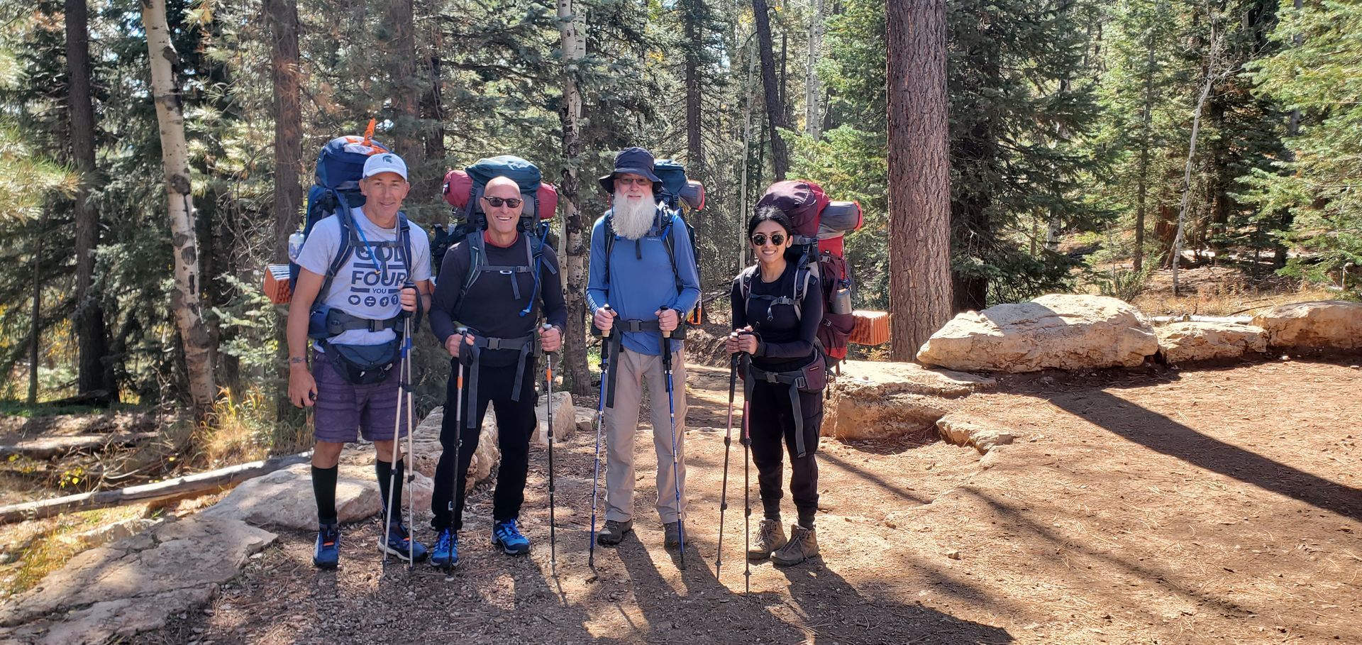 A group of people with backpacks are standing next to each other in the woods.