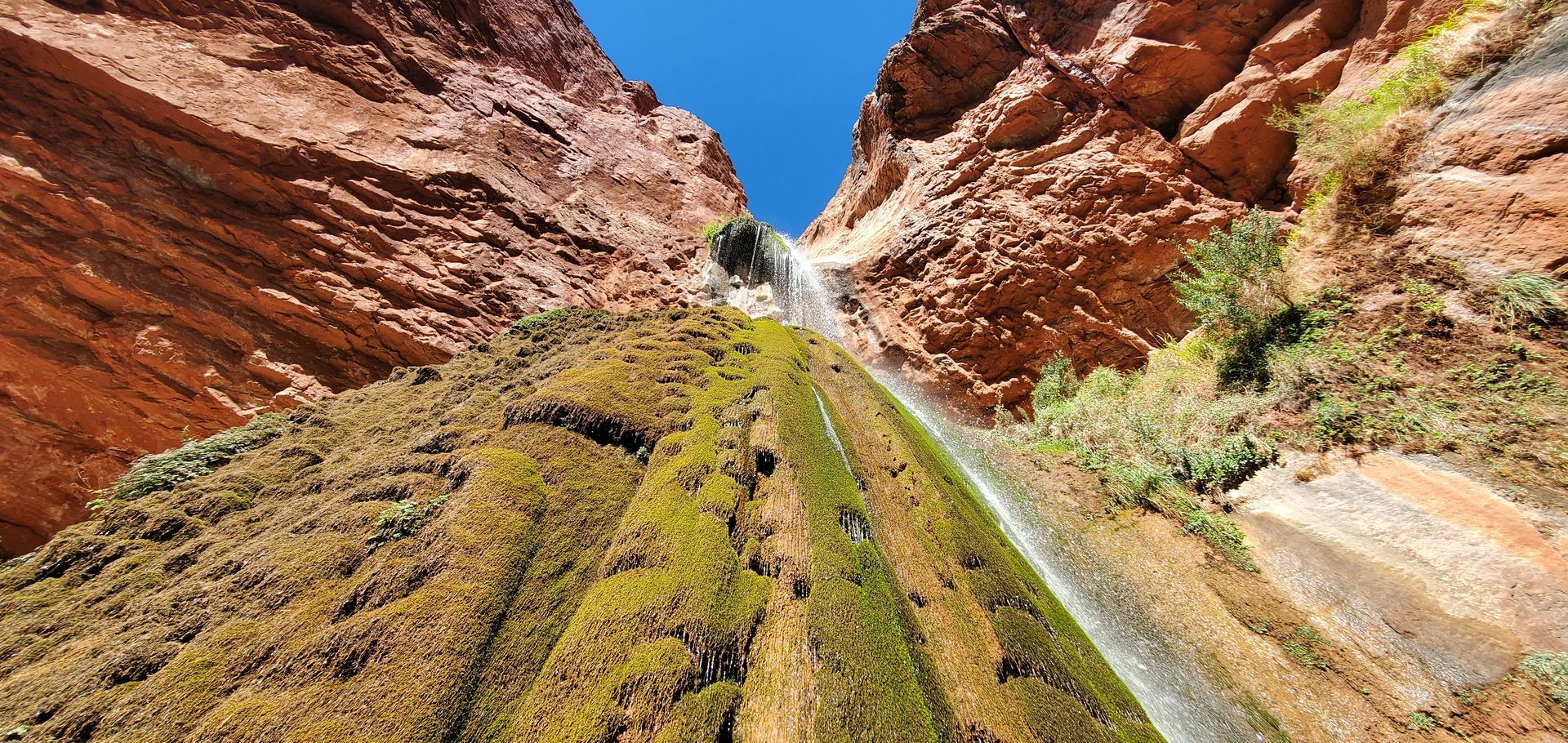 Looking up at a waterfall in the middle of a canyon.
