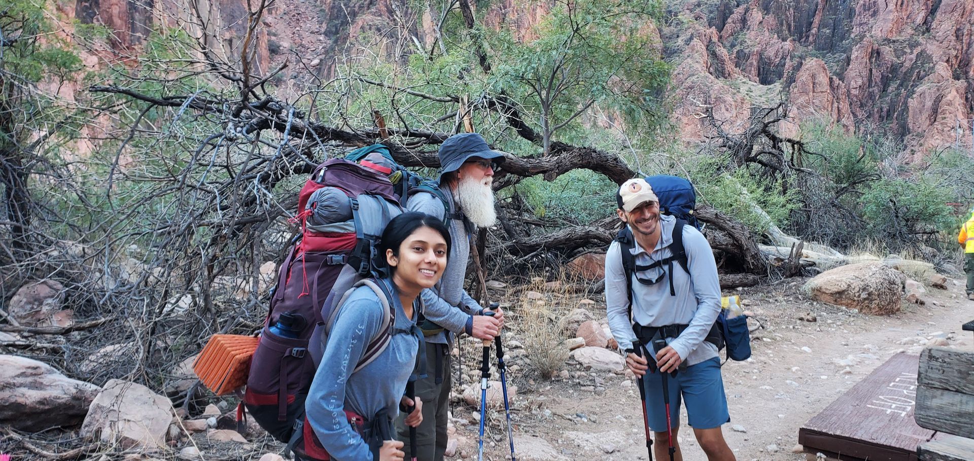 A group of people with backpacks are standing next to each other on a trail.