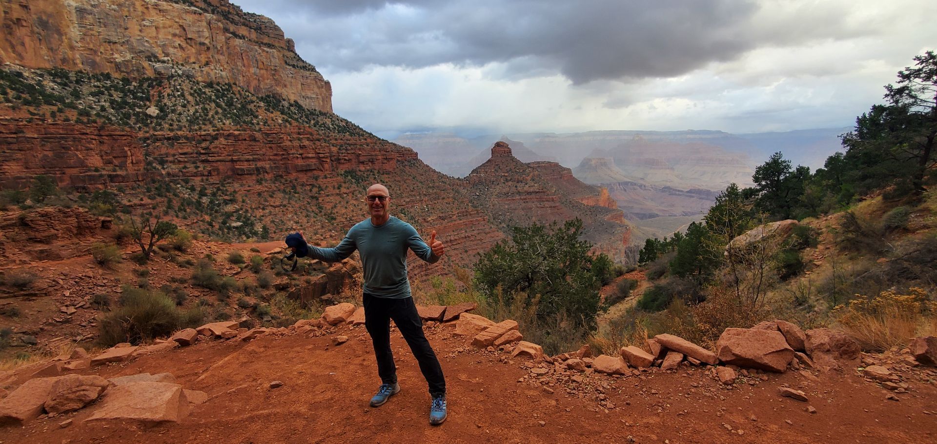 A man is standing on top of a dirt hill in the desert.