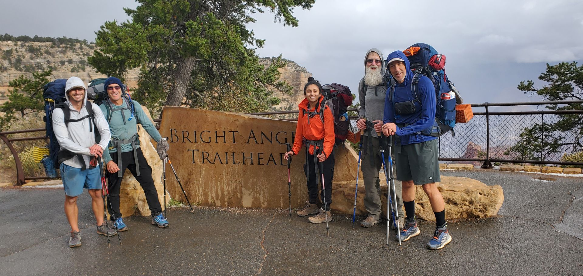 A group of people standing in front of a sign that says bright angel trailhead