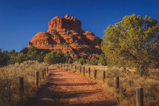 A dirt path leading to a mountain in the desert.