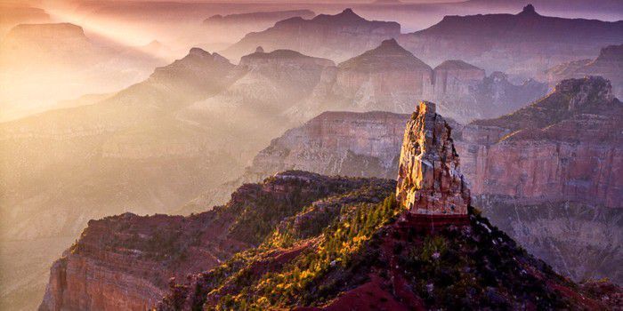 The sun is shining through the clouds on the mountains in the grand canyon.