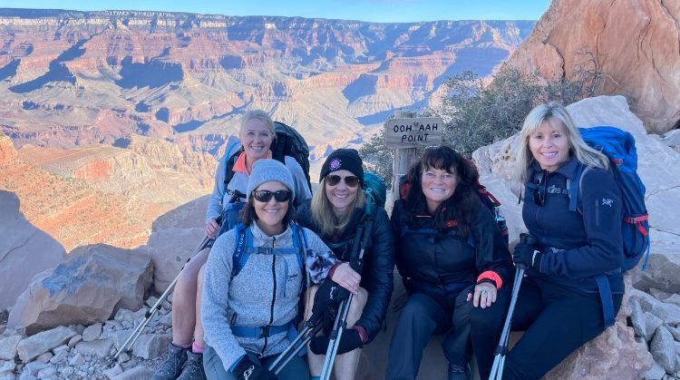 A group of women are posing for a picture on top of a mountain.