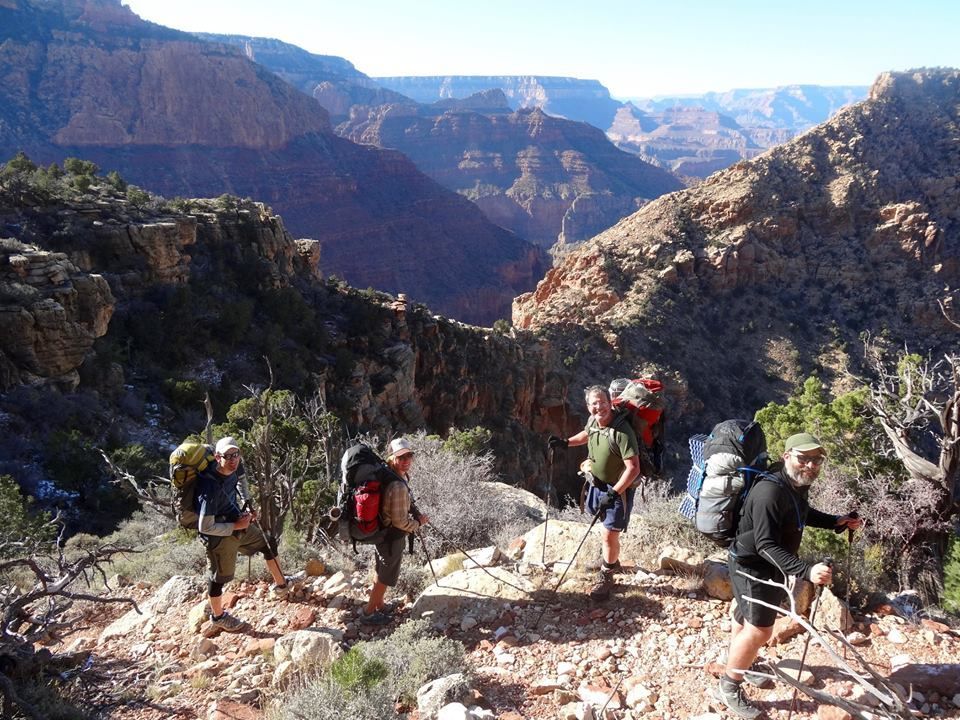 A group of people with backpacks are hiking up a mountain