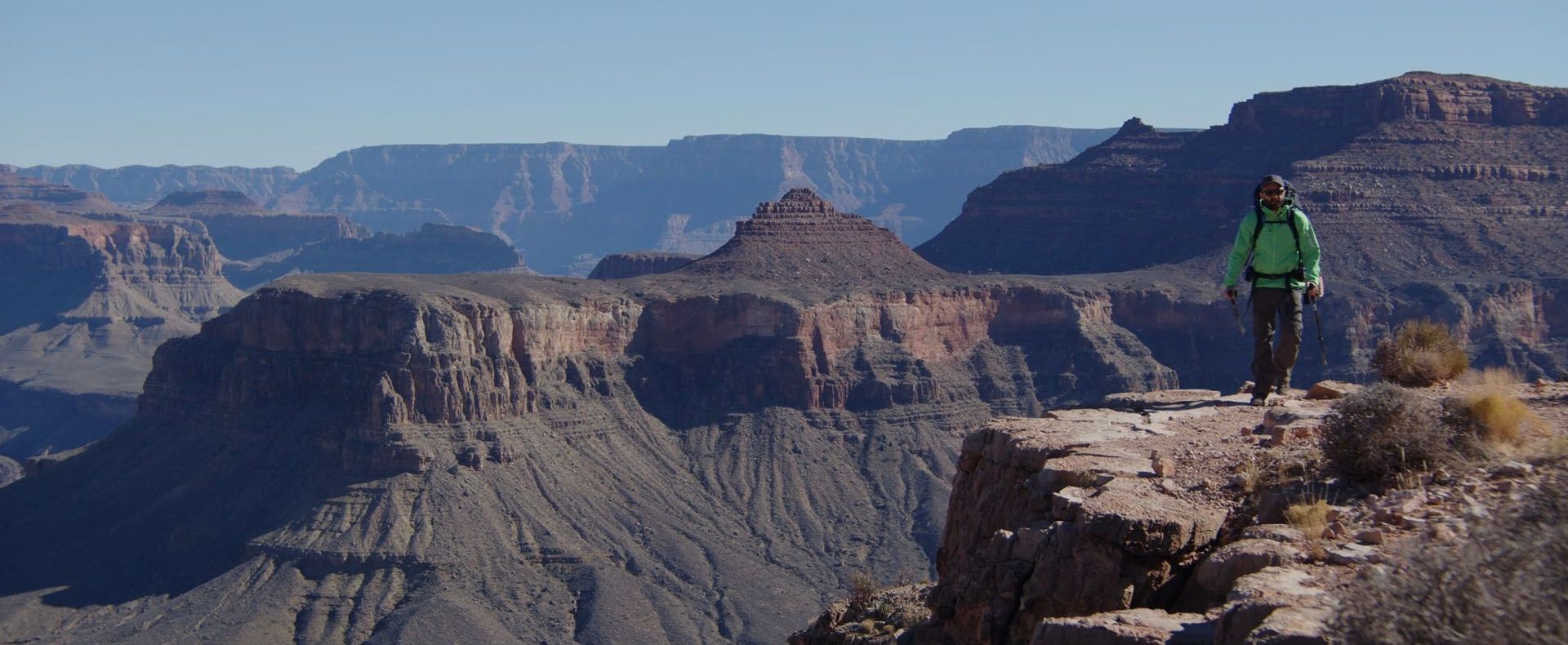 A person is standing on a cliff overlooking a canyon.