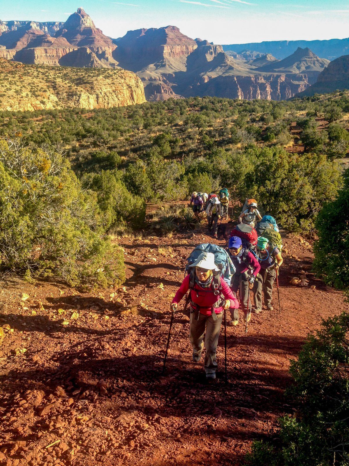 A group of people are hiking down a dirt path.