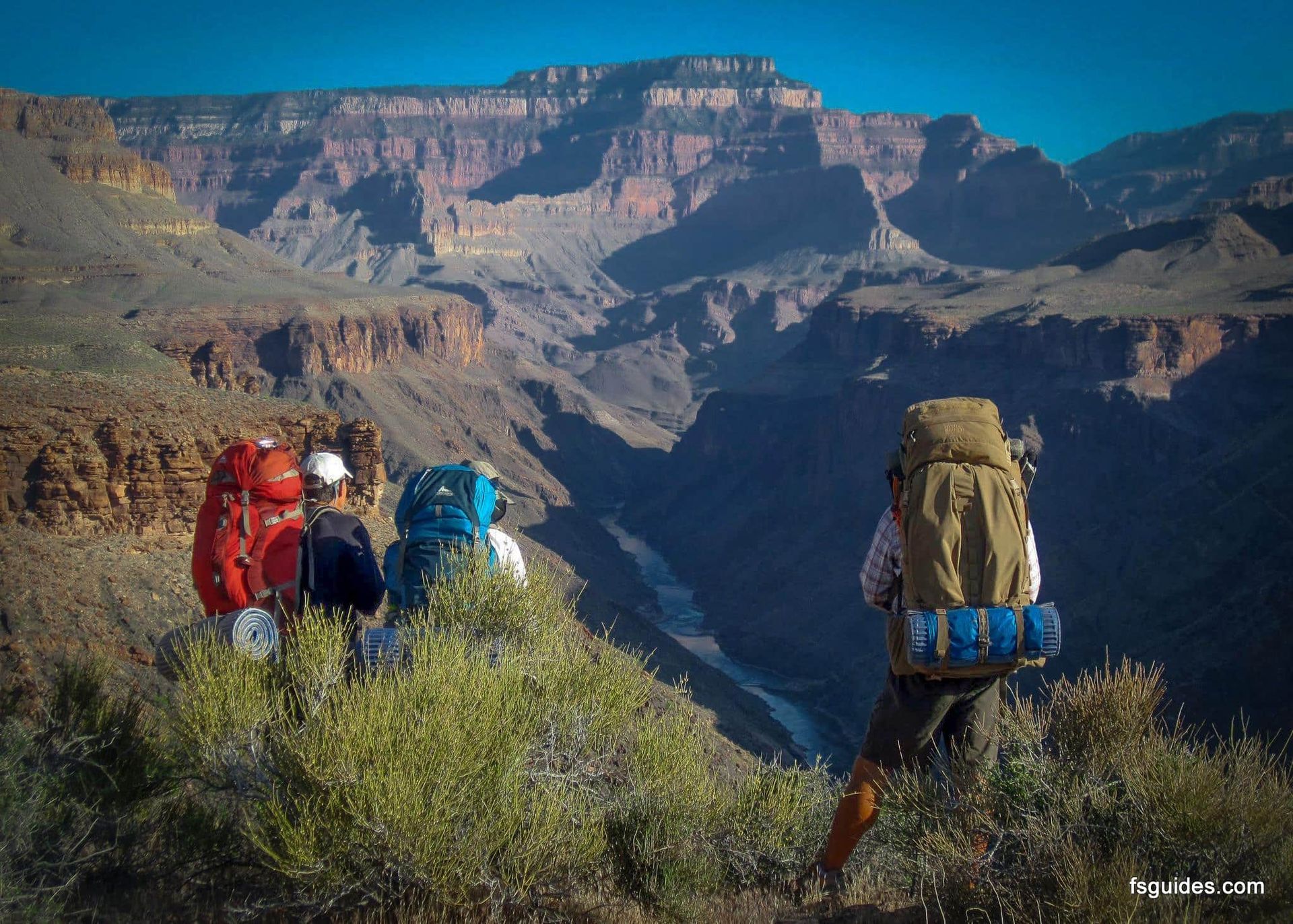 A group of people with backpacks are standing on top of a mountain.