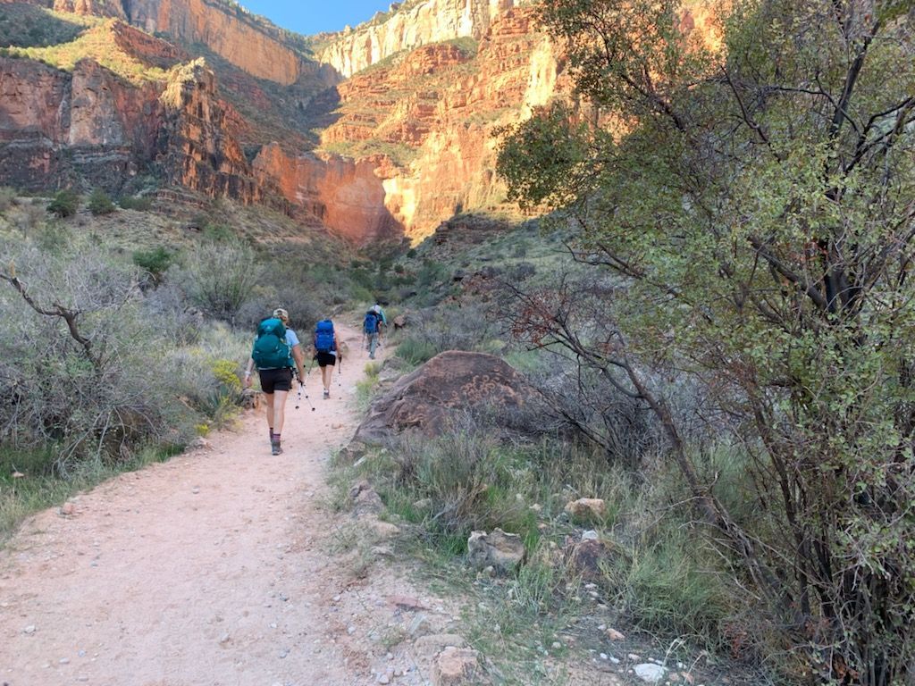 A group of people are walking down a dirt path in the mountains.