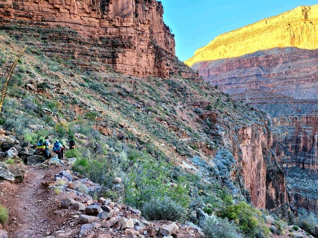 A group of people are hiking down a trail in the mountains.