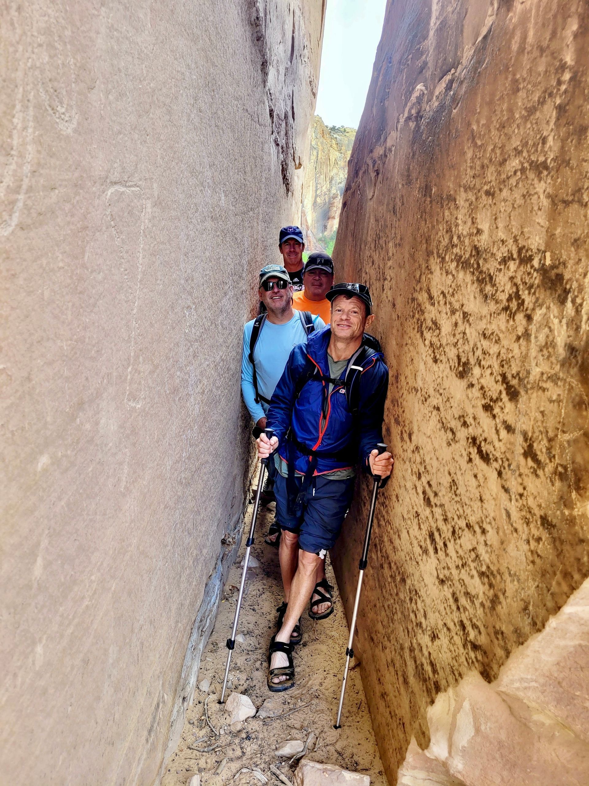 A group of people are hiking through a narrow canyon.