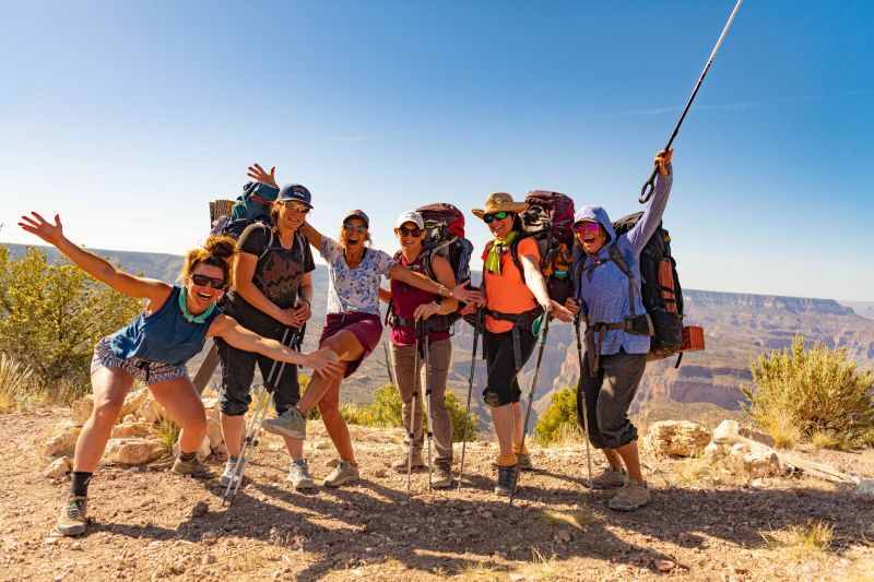 Group of hikers celebrating on a sunny overlook, overlooking a canyon.