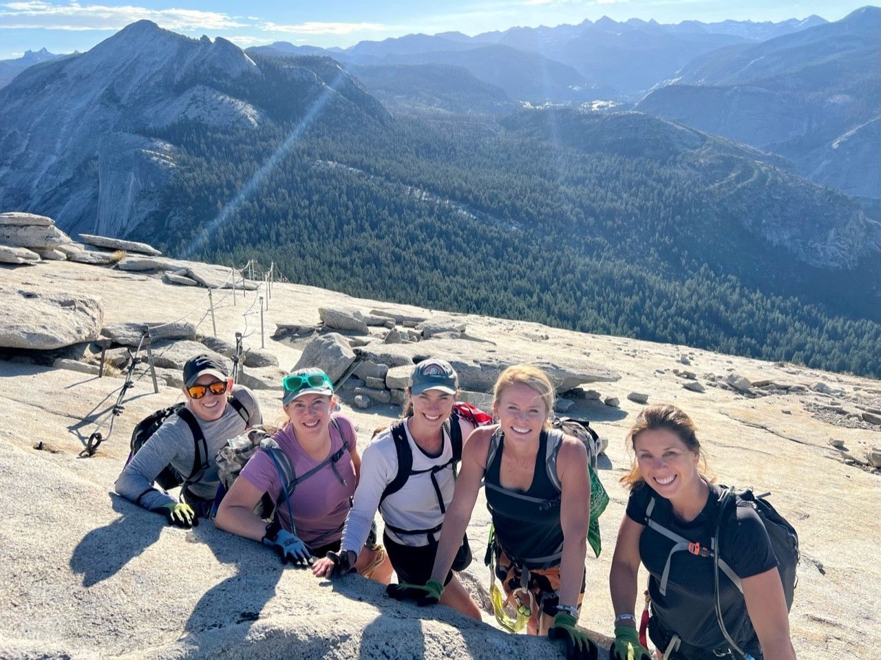 A group of women are posing for a picture on top of a mountain.