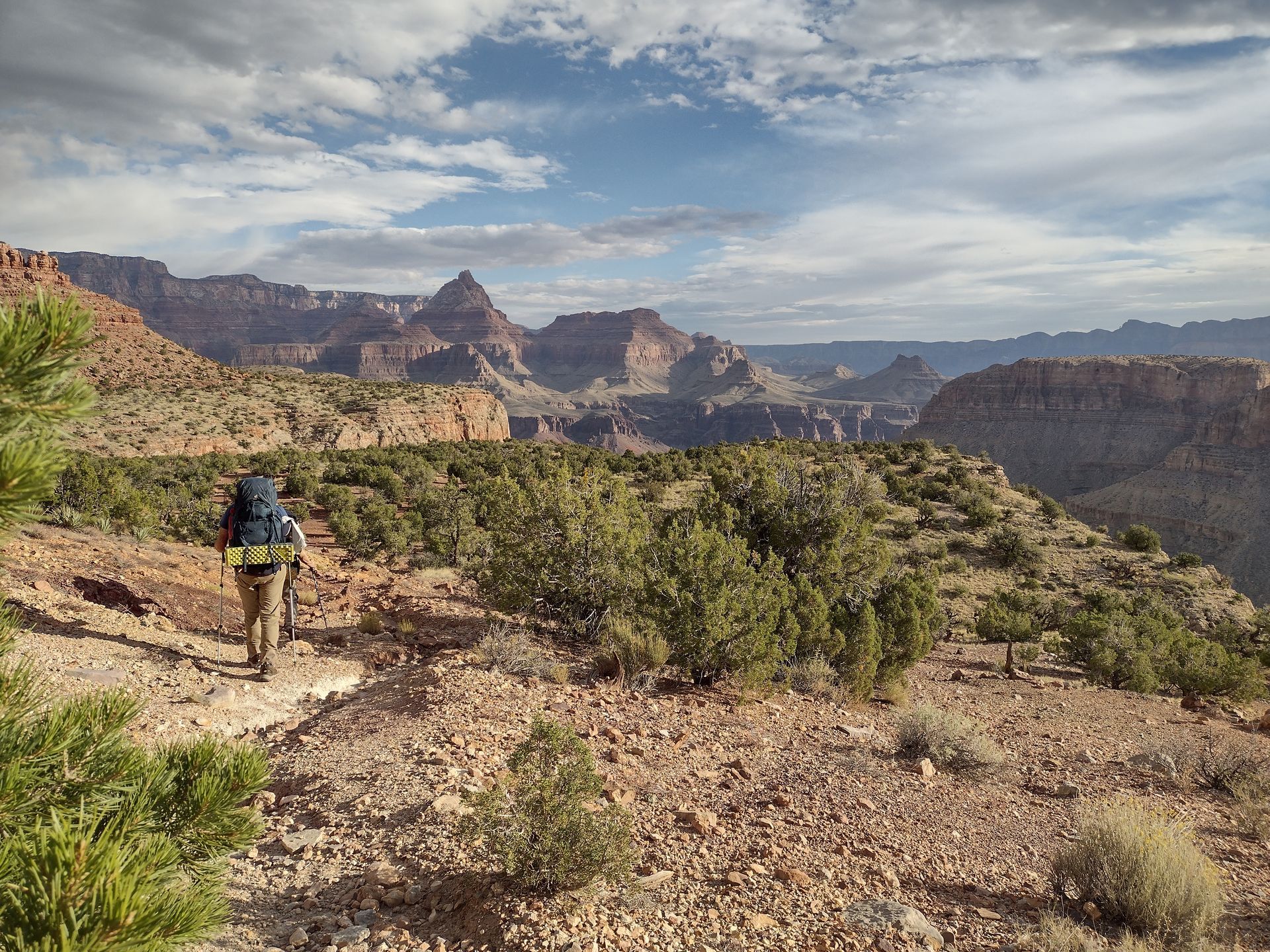 A person with a backpack is walking on a trail in the mountains.