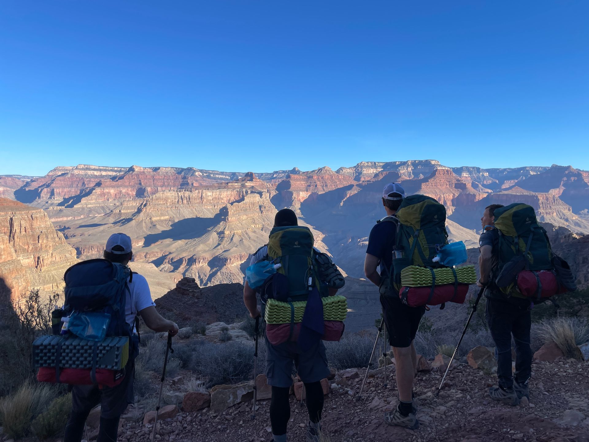 A group of people with backpacks standing on top of a mountain