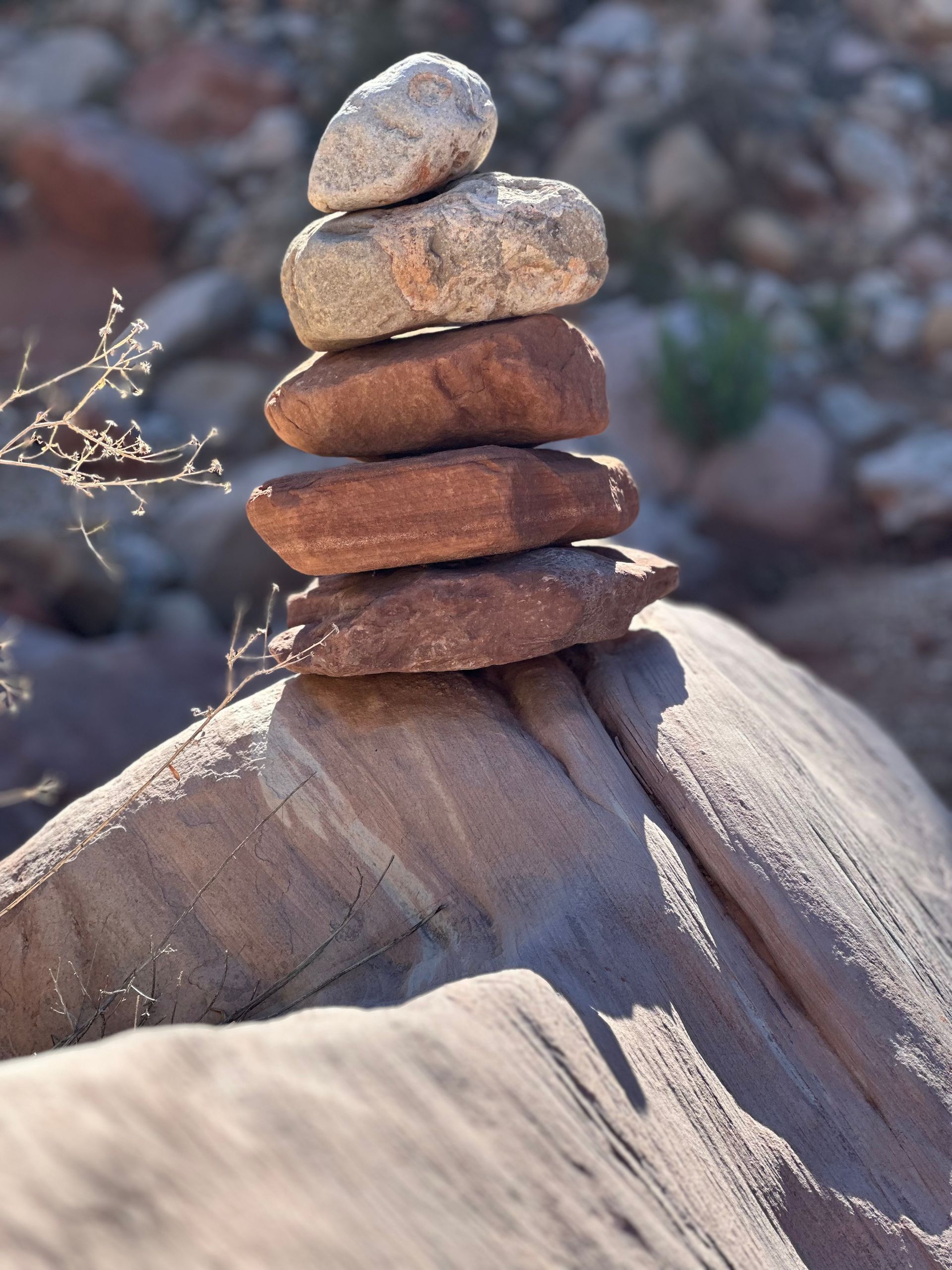 Stack of reddish-brown stones balanced on a larger rock, outdoors.