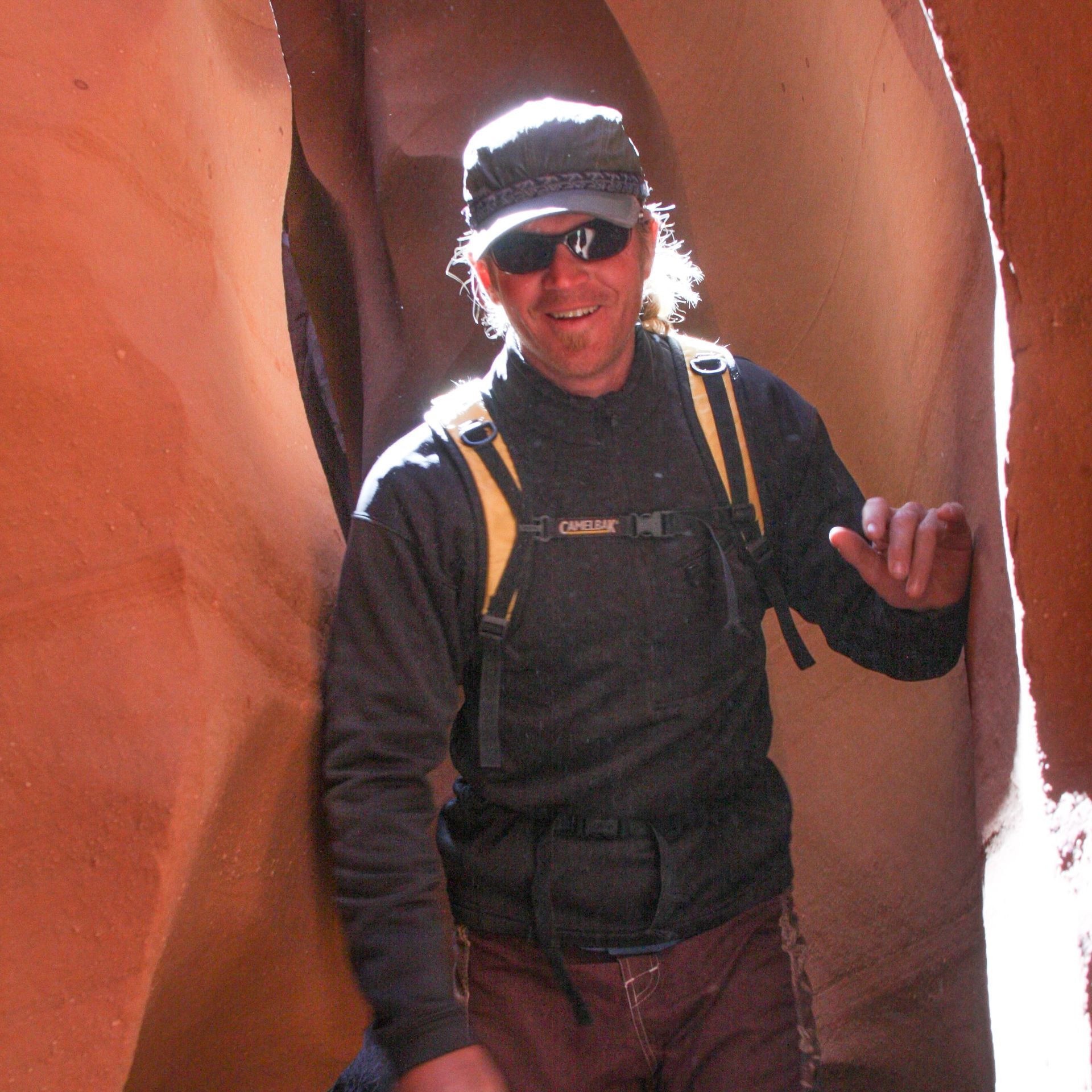 A man wearing sunglasses and a hat is standing in a cave