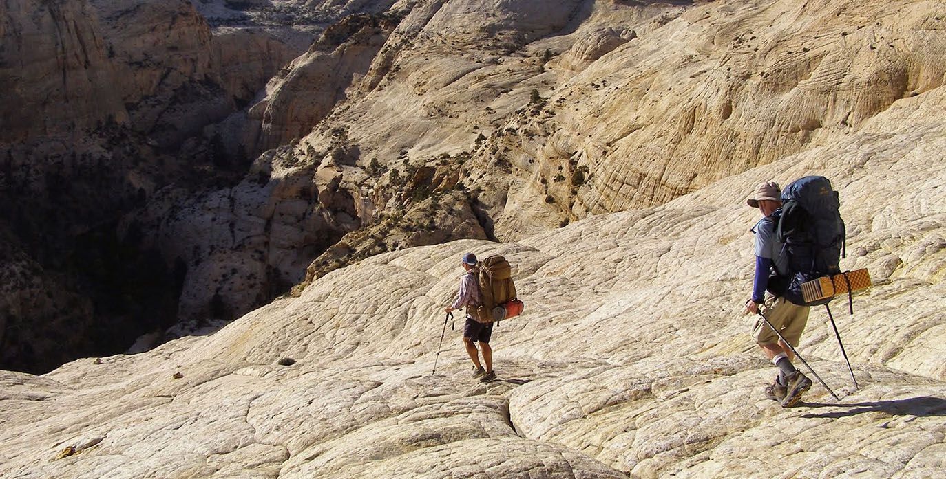 Two People With Backpacks Are Walking Down a Rocky Hillside