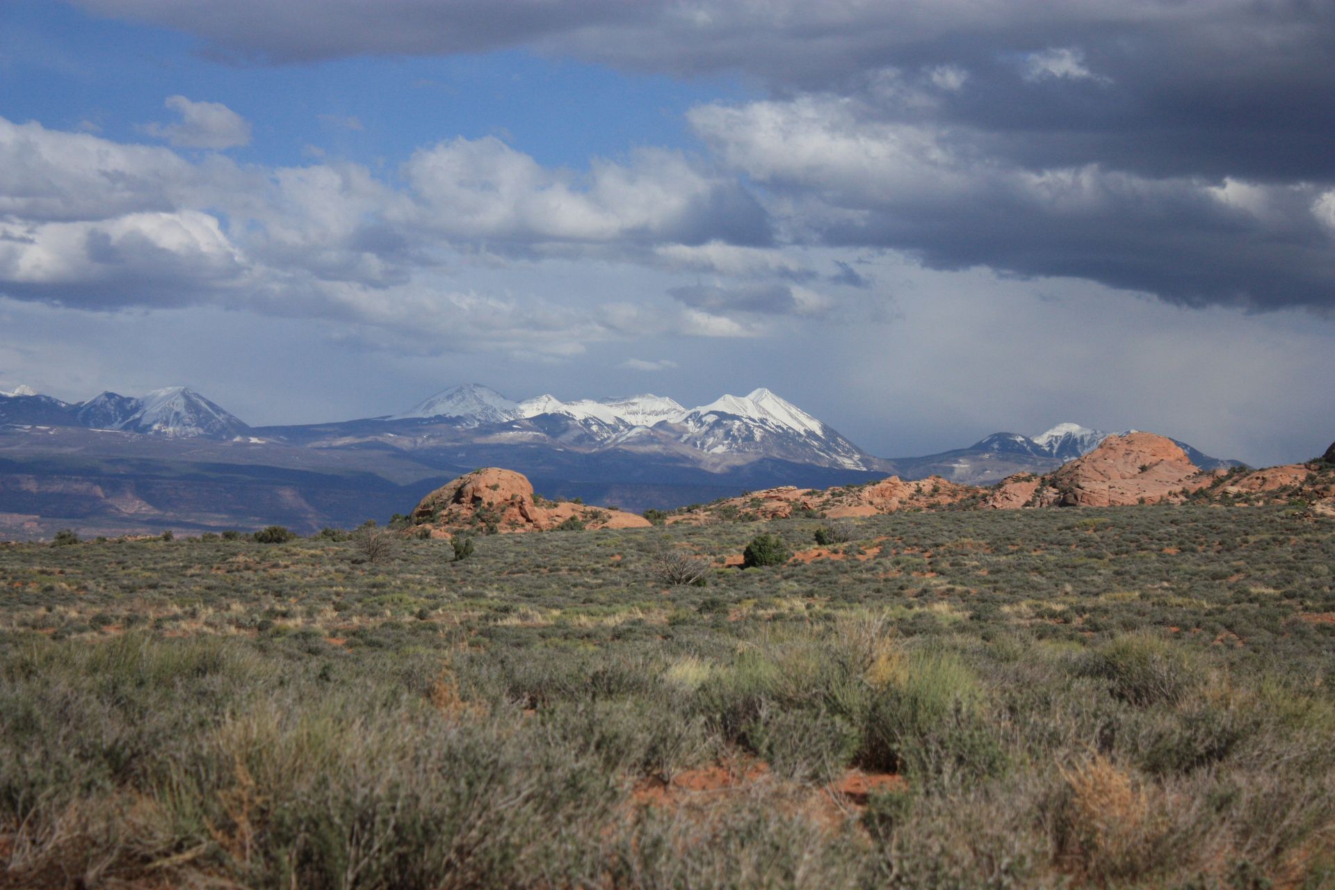 A desert landscape with mountains in the background and a cloudy sky