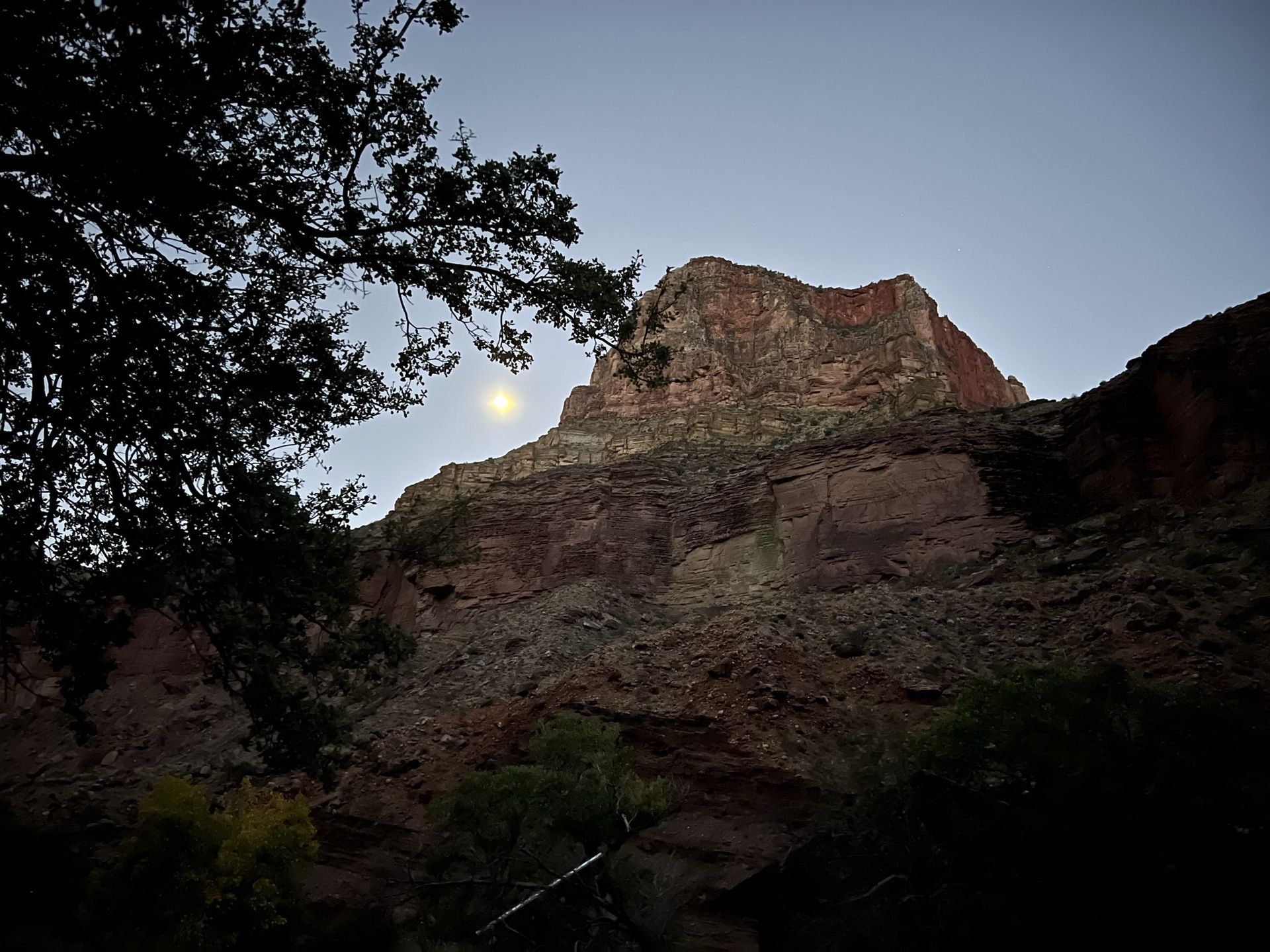 A full moon is visible in the sky above a mountain