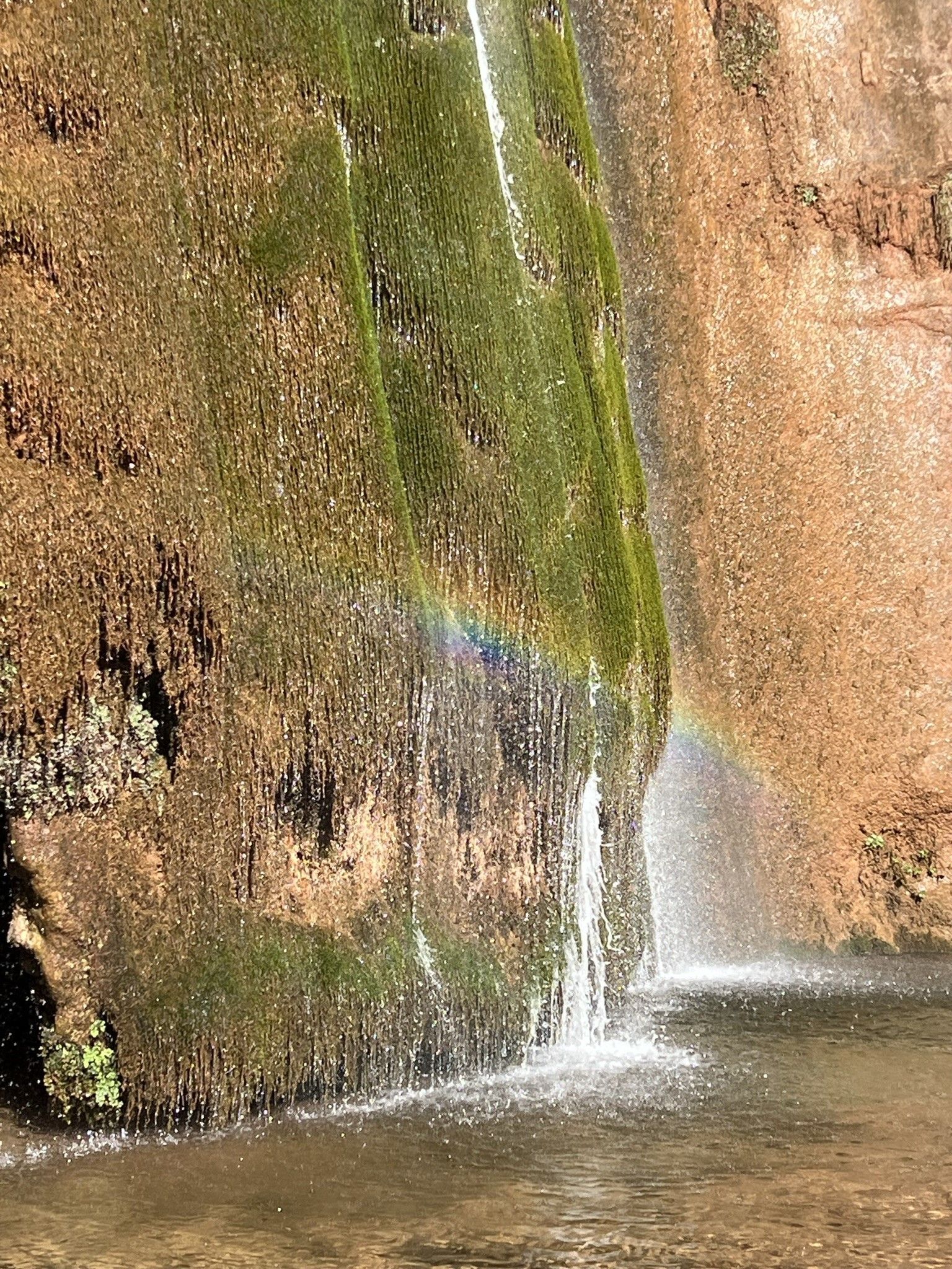A waterfall with a rainbow in the middle of it