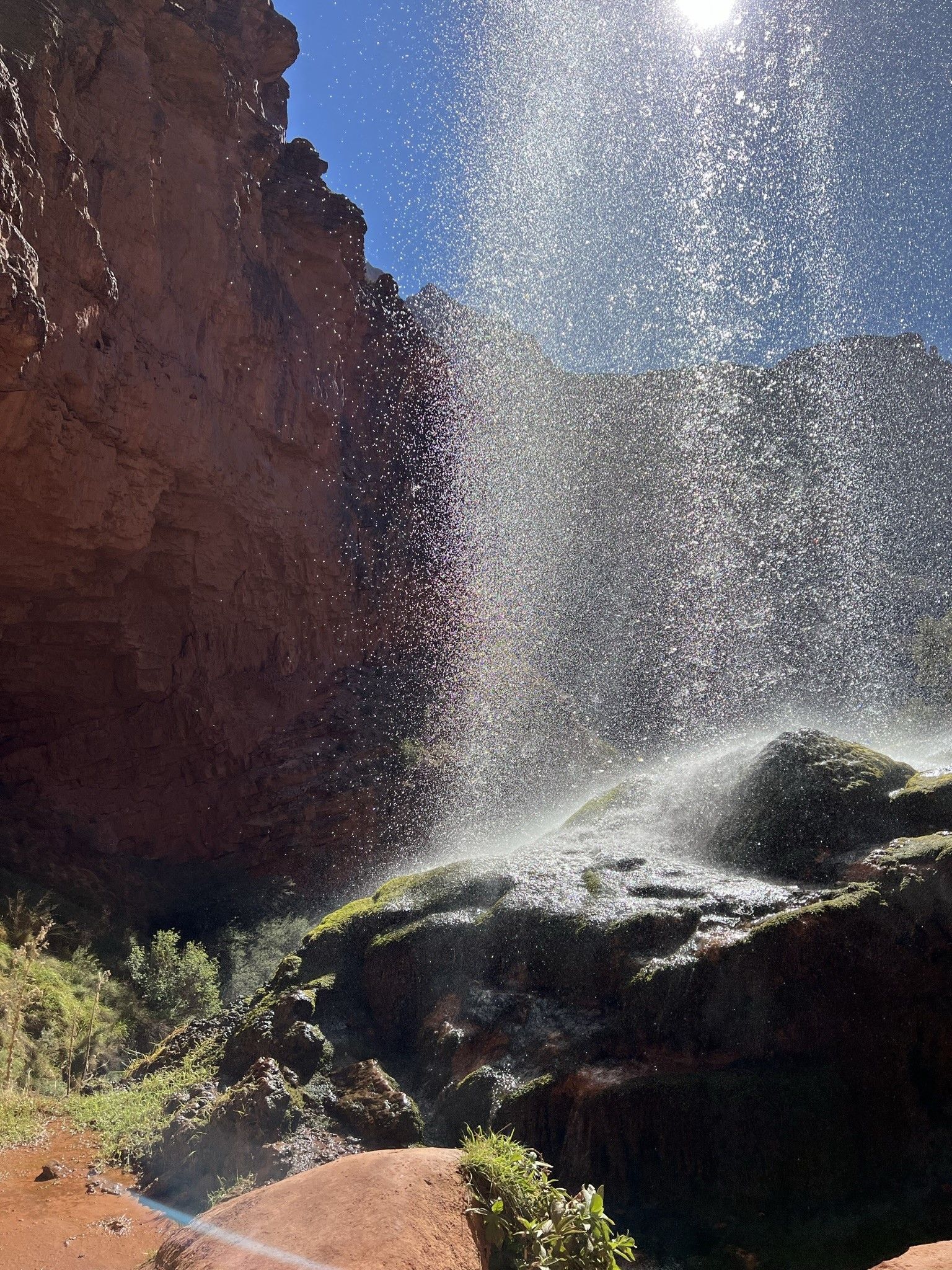 A waterfall is spraying water over a rocky cliff.