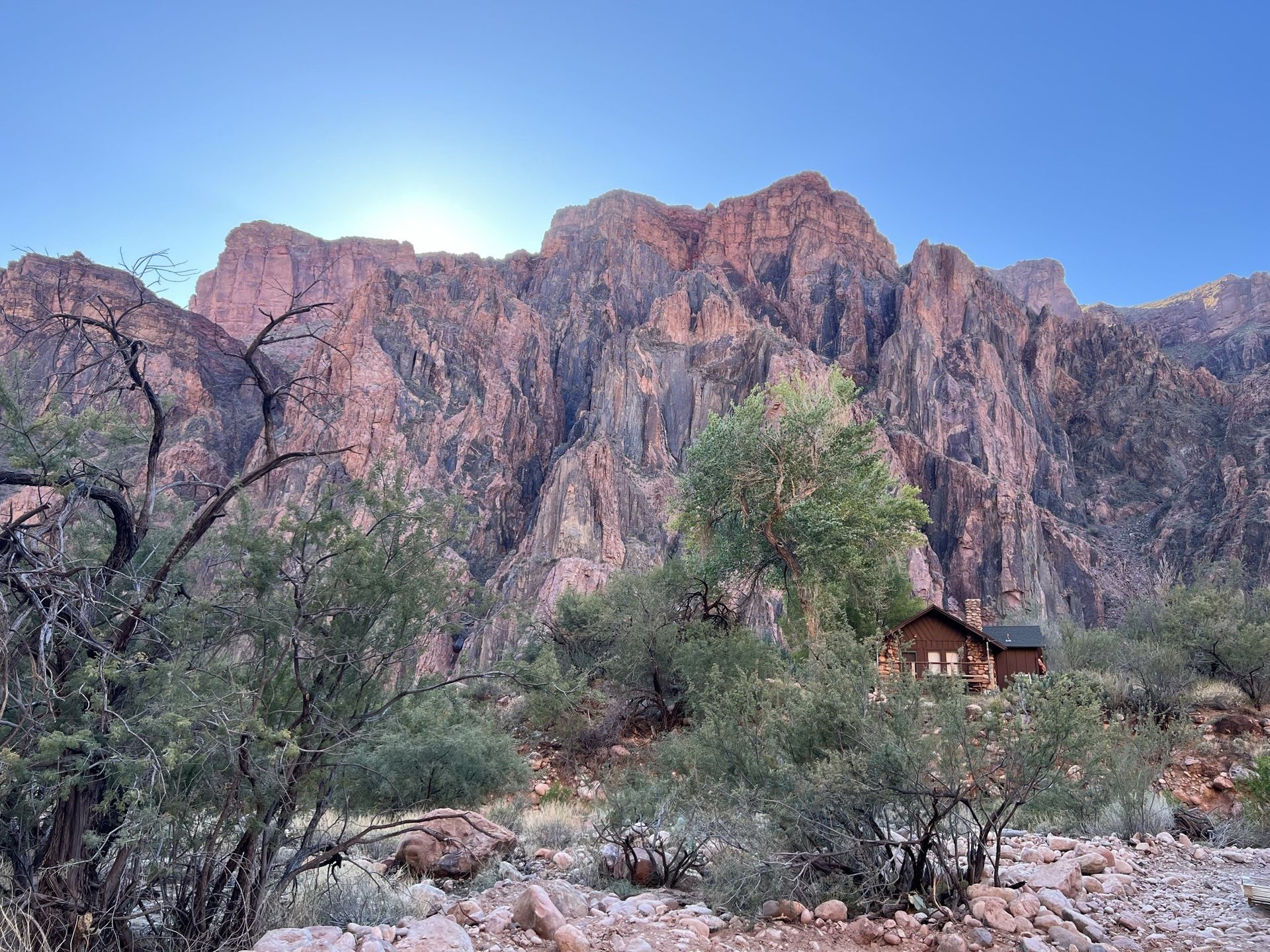 A house in the middle of a desert with a mountain in the background.