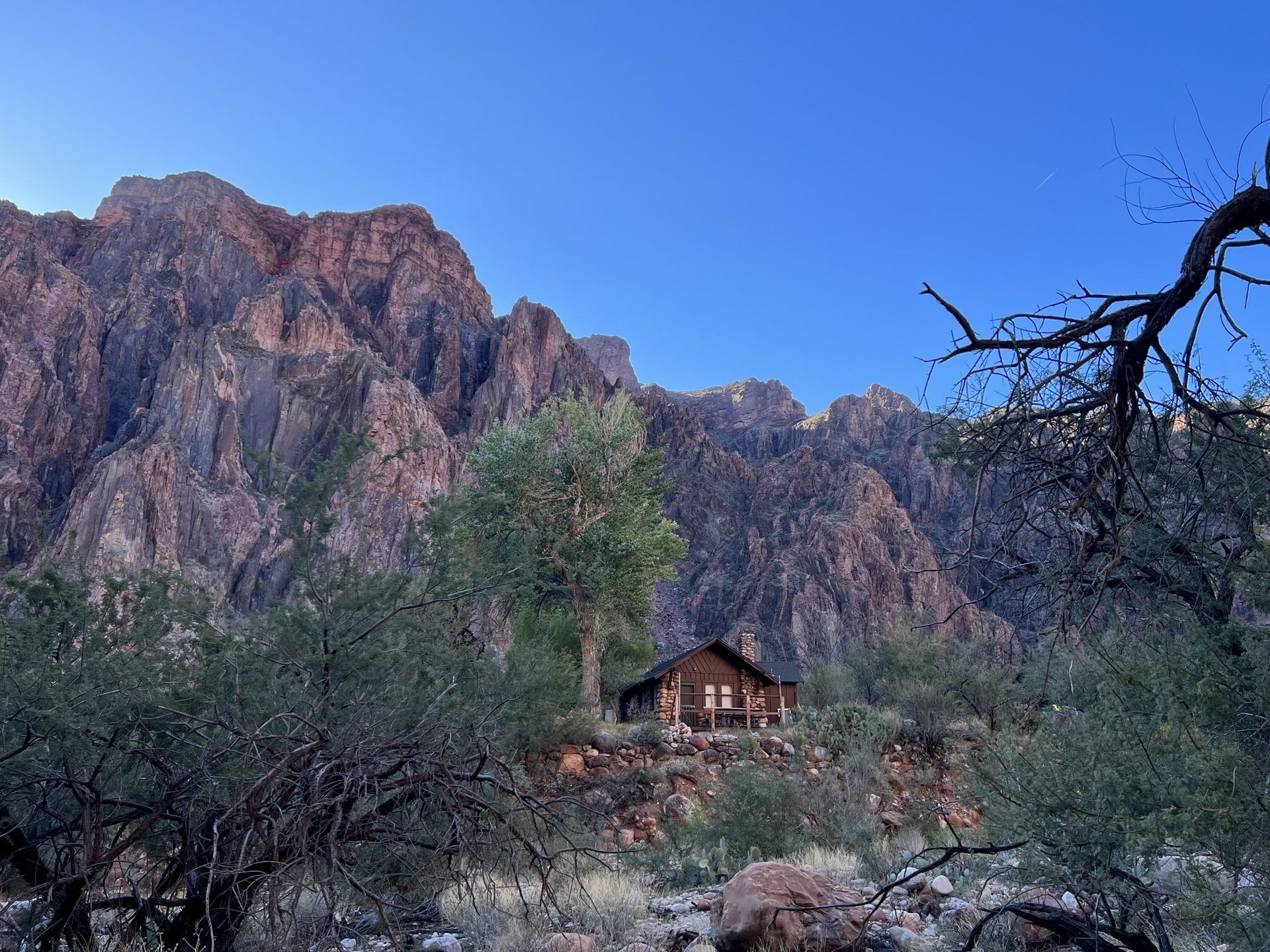 A cabin in the middle of a desert with mountains in the background