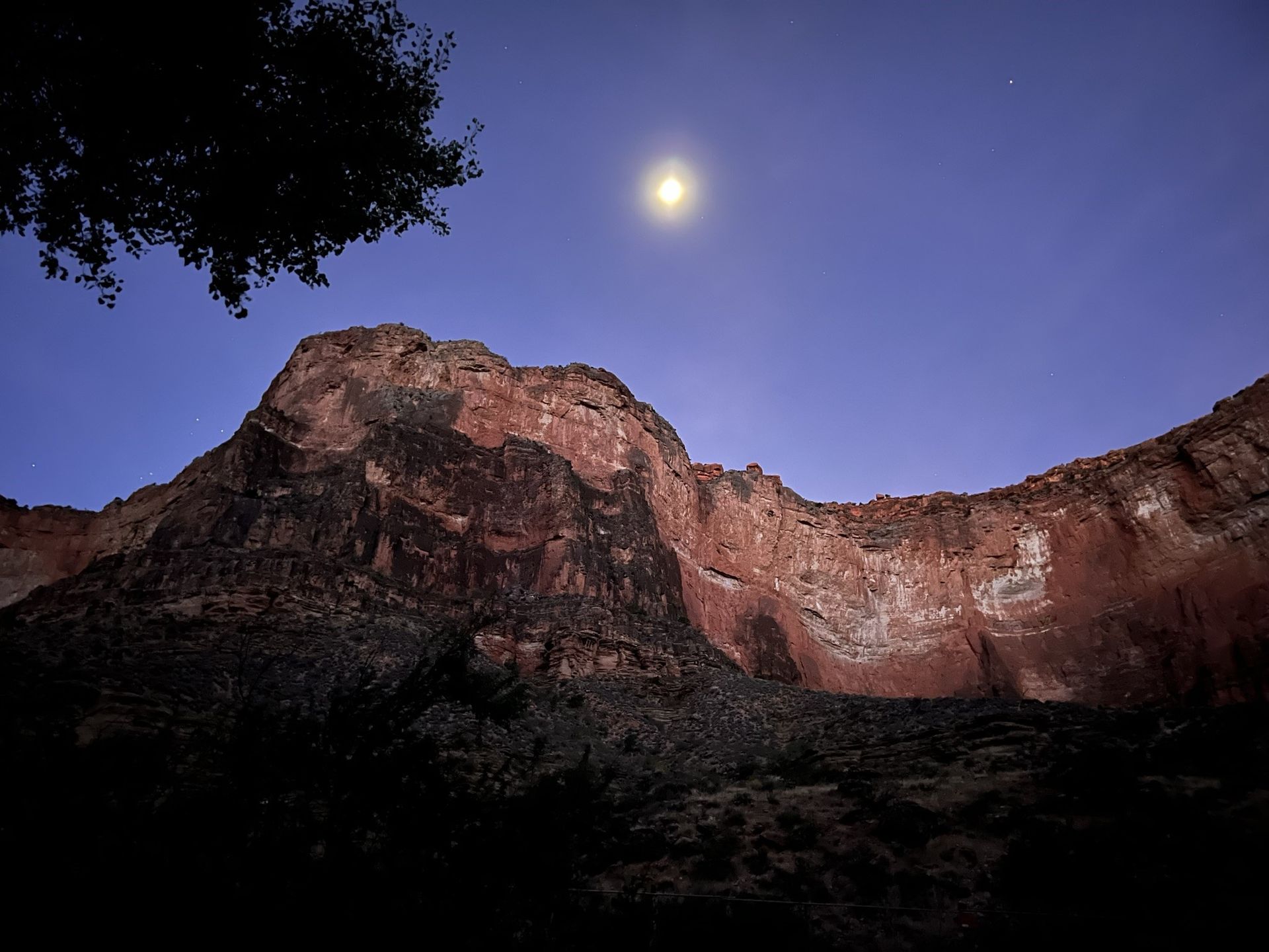 A full moon shines over a rocky mountain
