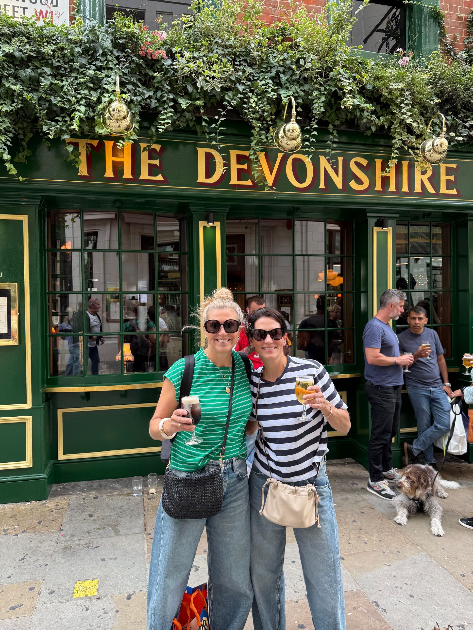 Two people with drinks pose in front of 