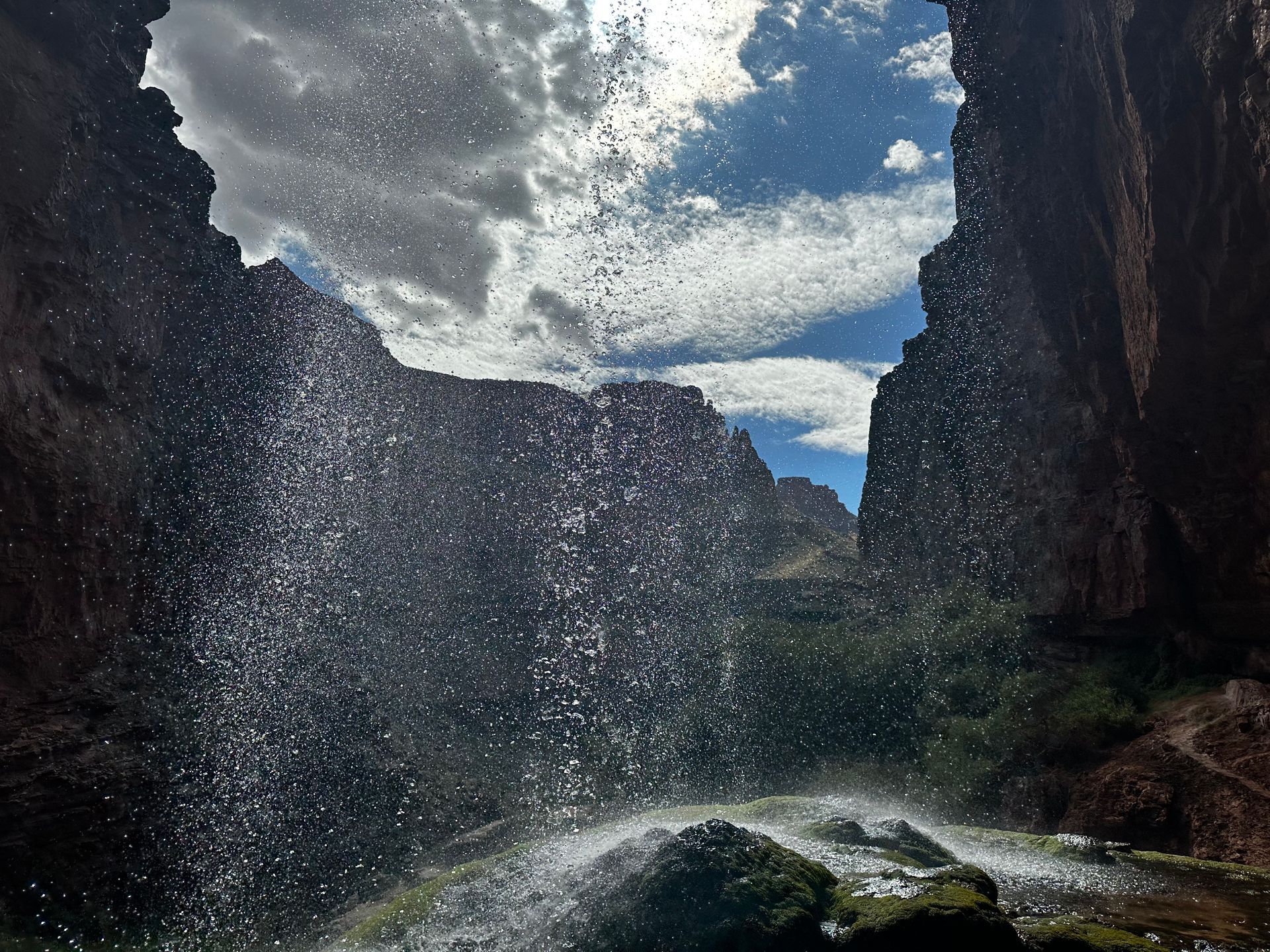 A waterfall in the middle of a canyon with a blue sky in the background