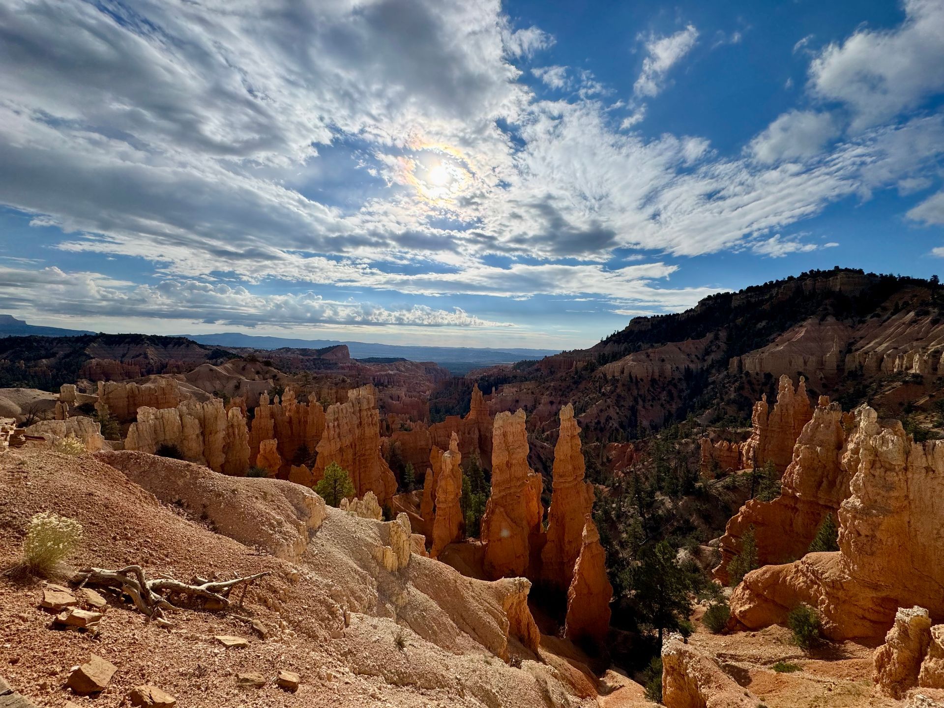 The sun is shining through the clouds over a canyon.