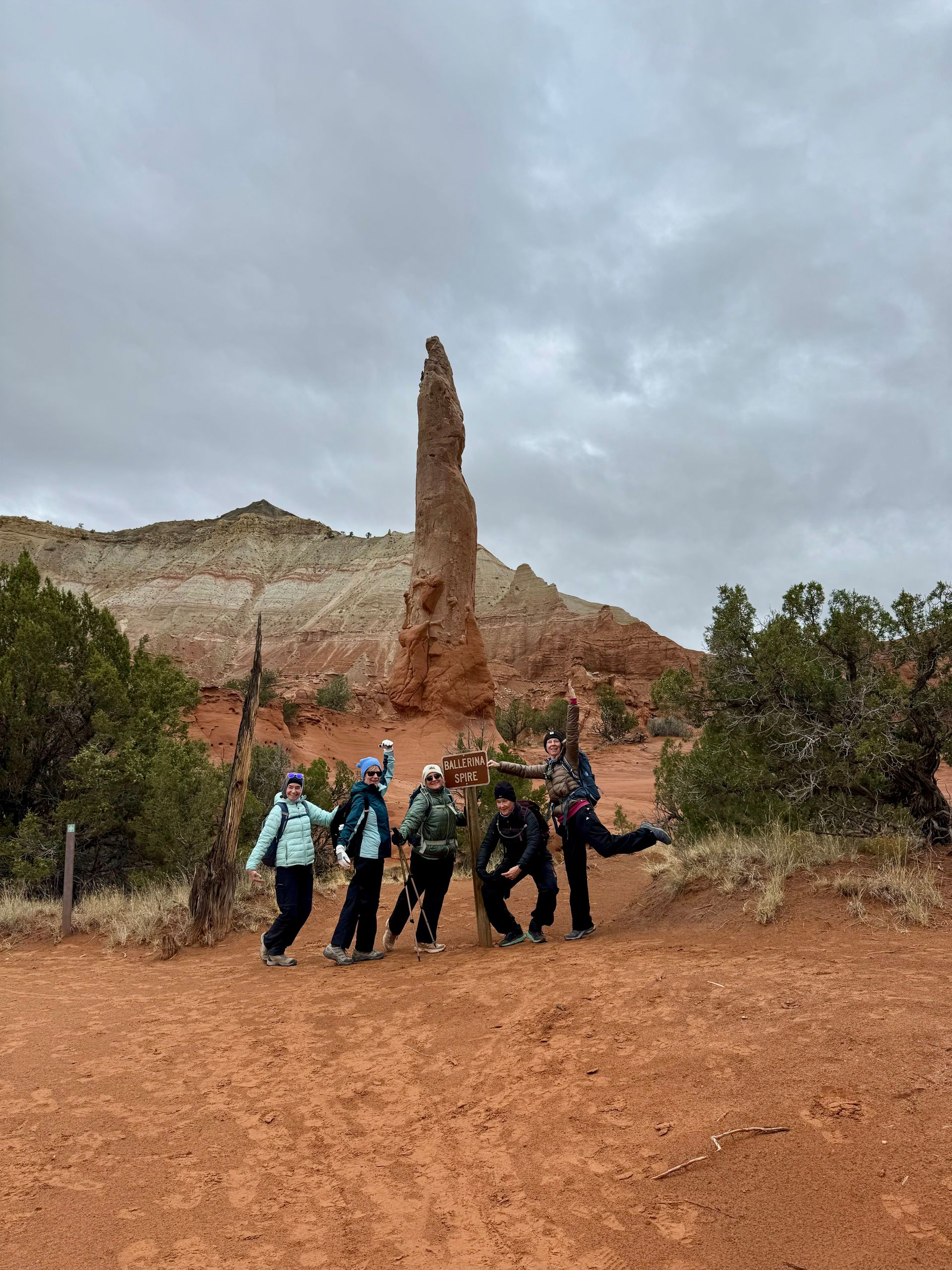 A group of people are posing for a picture in front of a large rock formation.