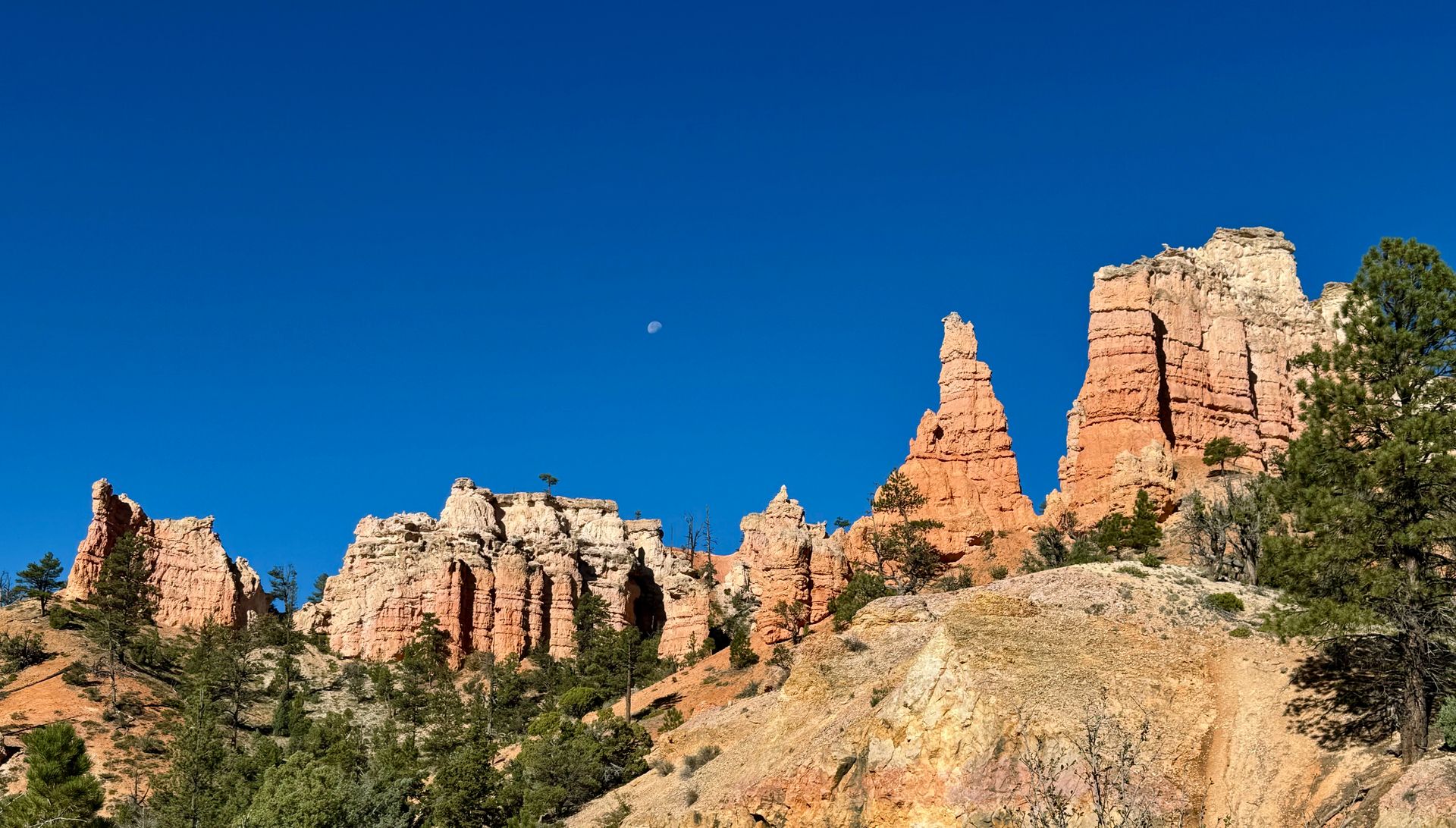 A mountain with a blue sky and a moon in the background