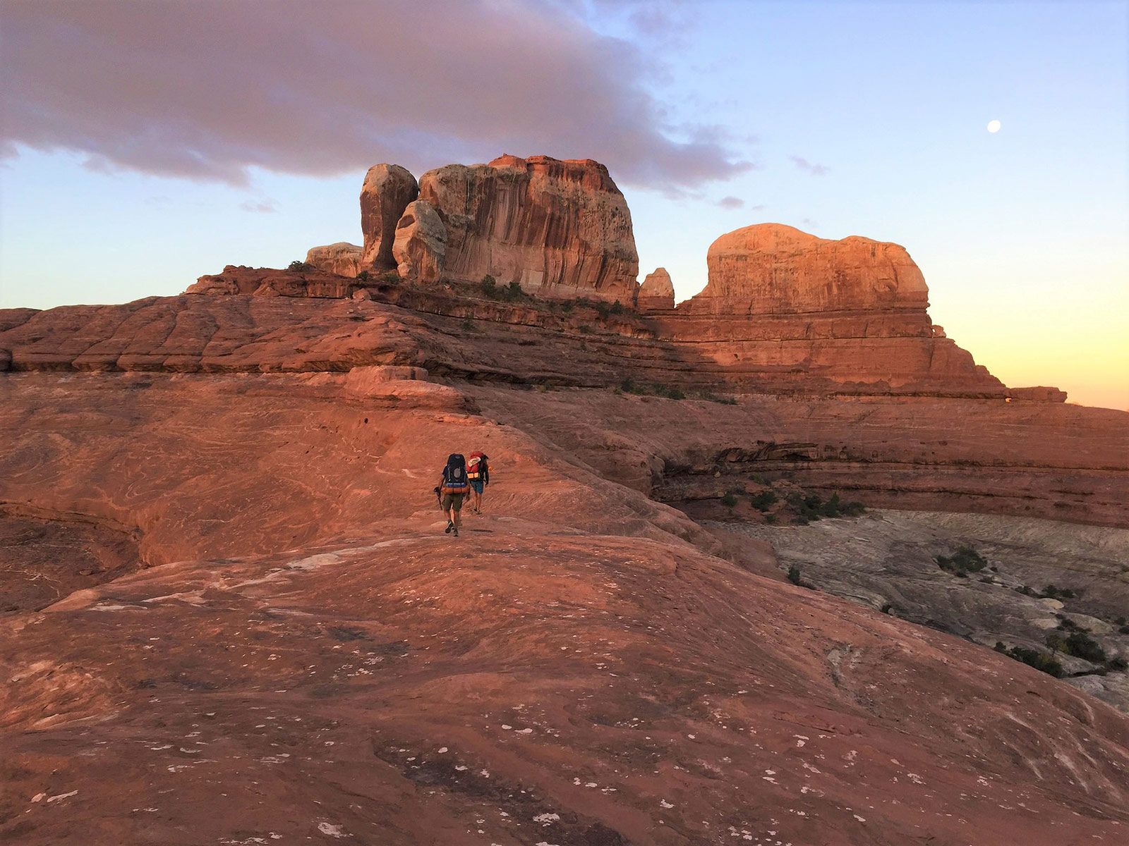 A couple of people standing on top of a rocky hill.