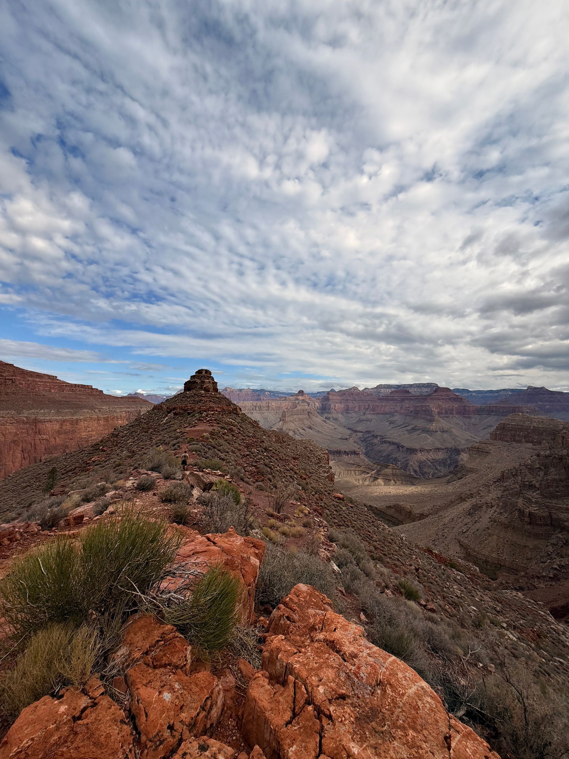Red rock mountain range under a cloudy sky.