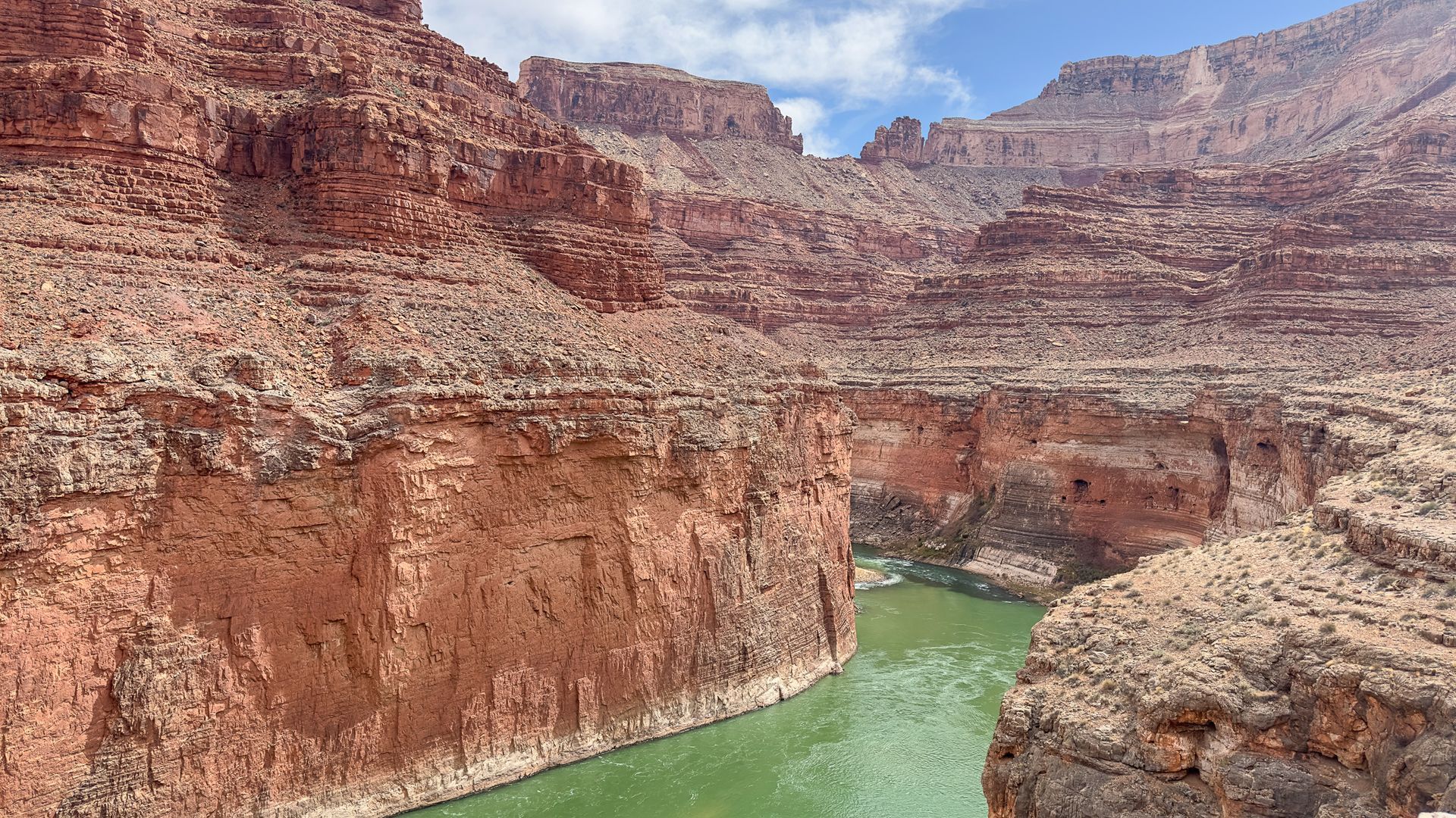 Red rock canyon with a green river winding through it.