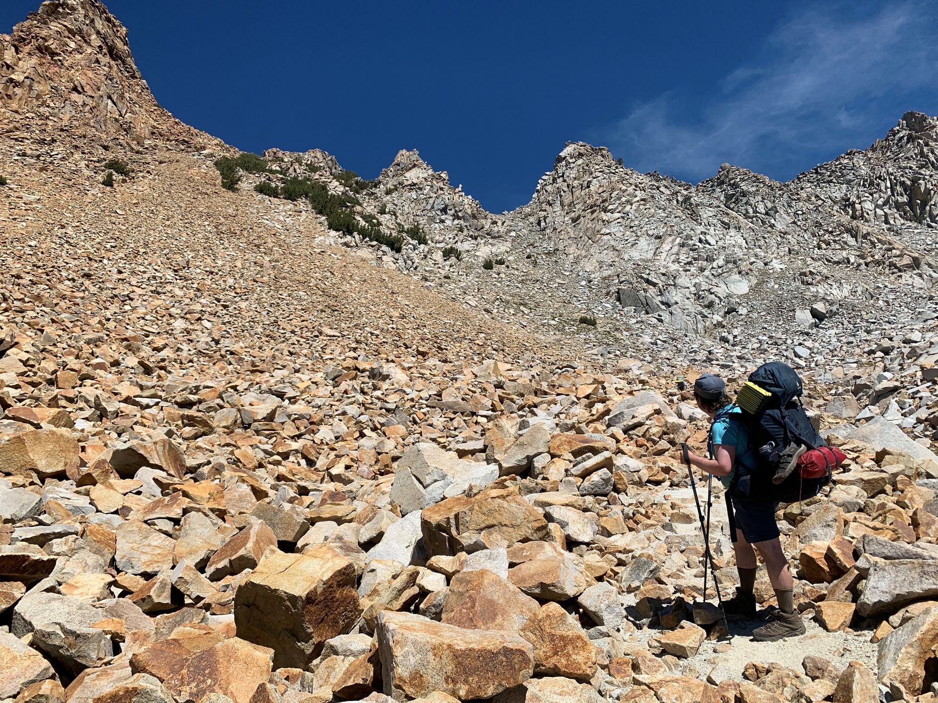 A person with a backpack is walking through a rocky area.
