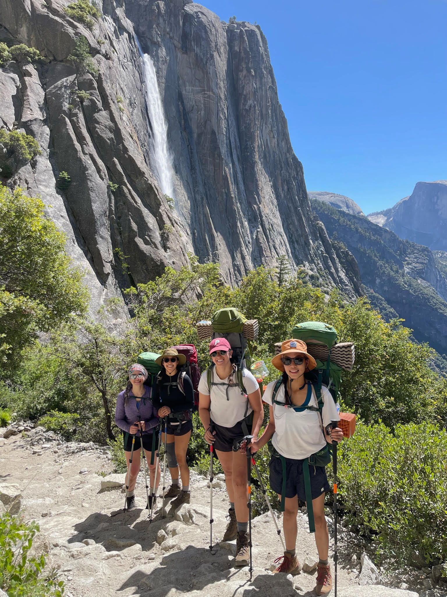 A group of people are hiking up a mountain with a waterfall in the background.