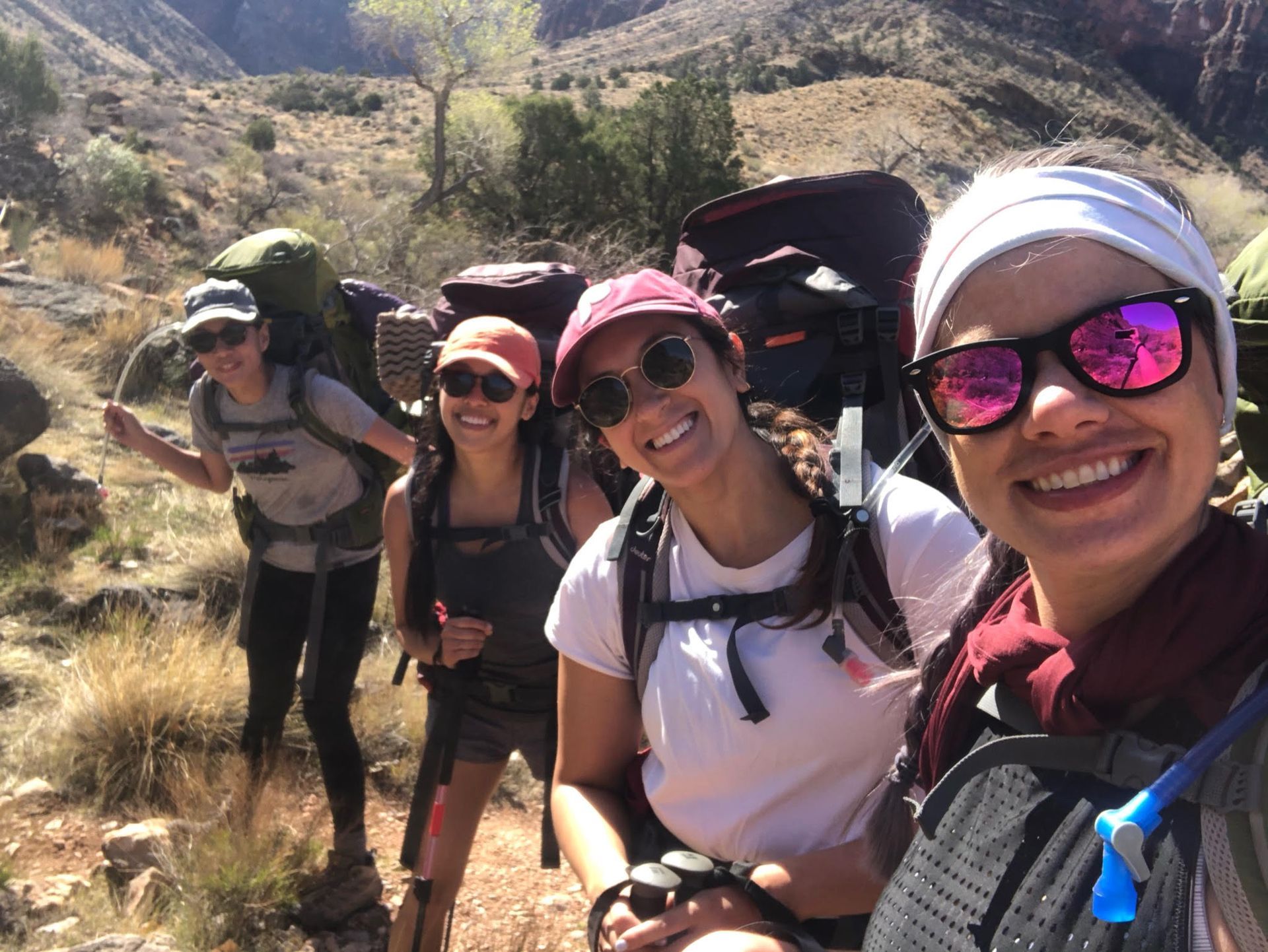 A group of women are hiking in the mountains and smiling for a picture.
