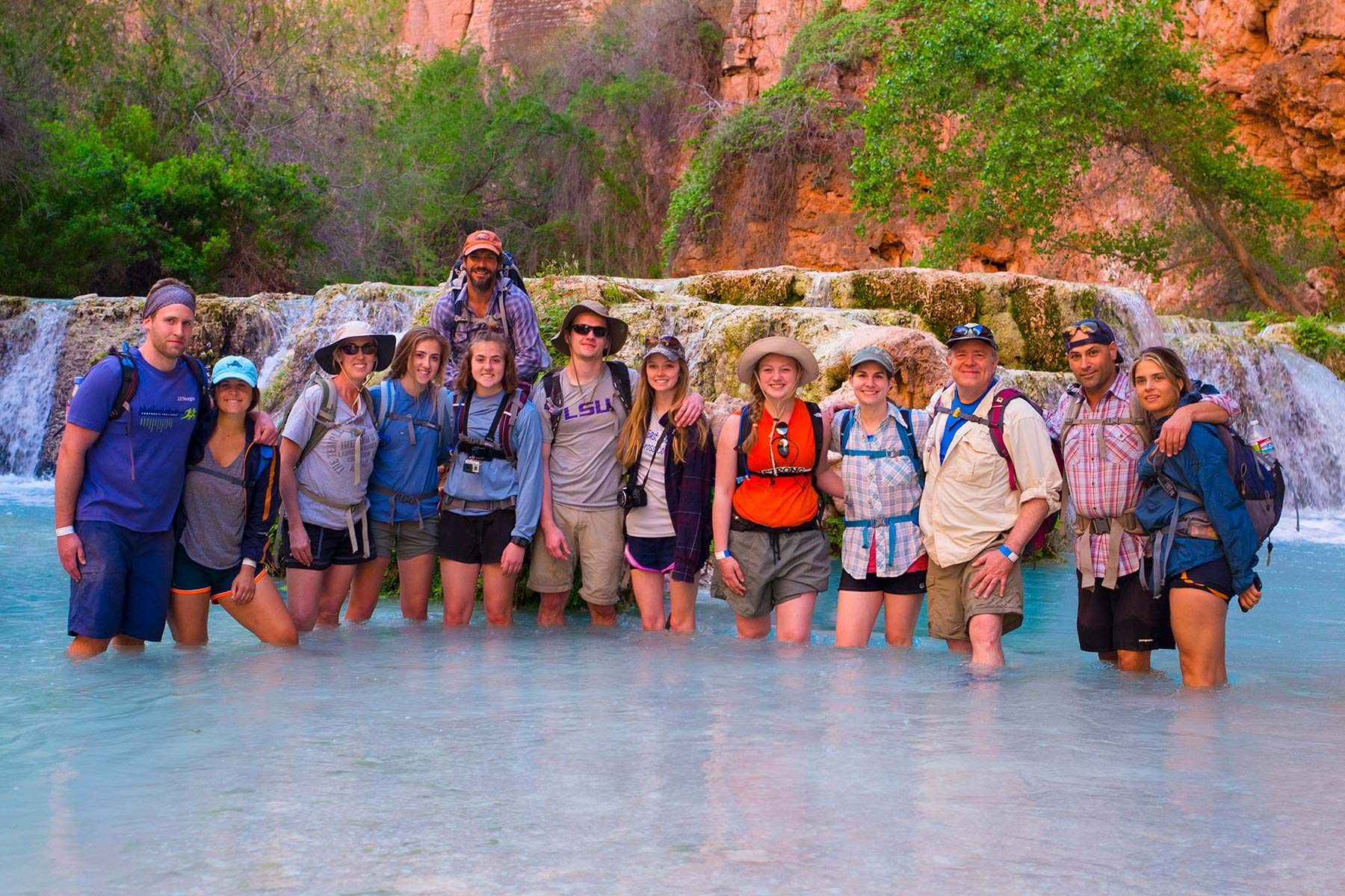 A group of people are posing for a picture in front of a waterfall.