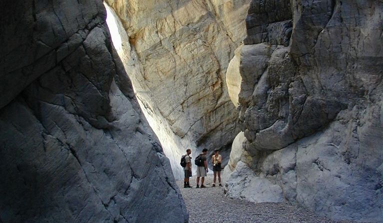 People walk through a towering canyon