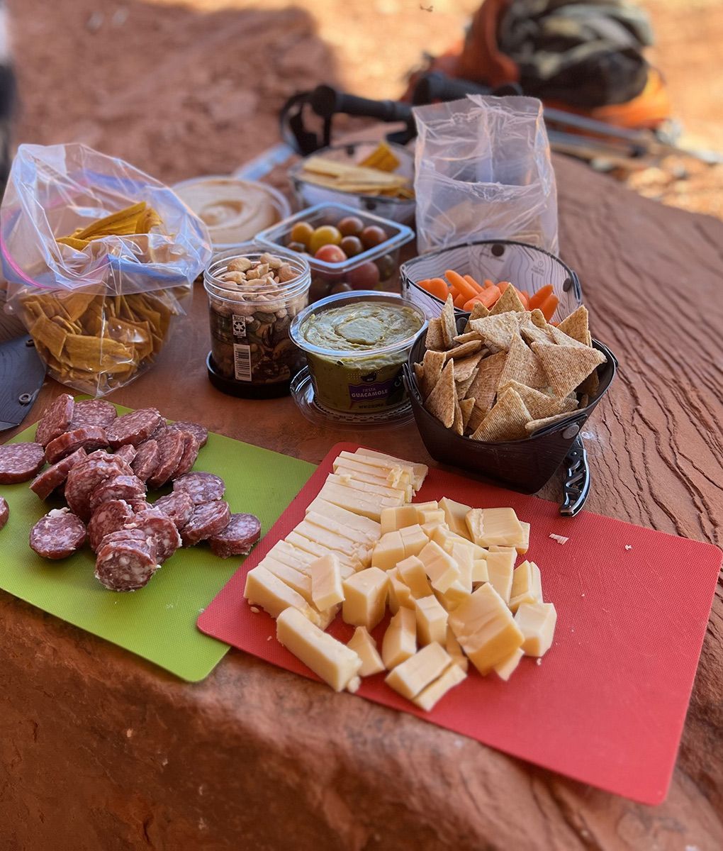 A table topped with a variety of food including sliced cheese and sausage.